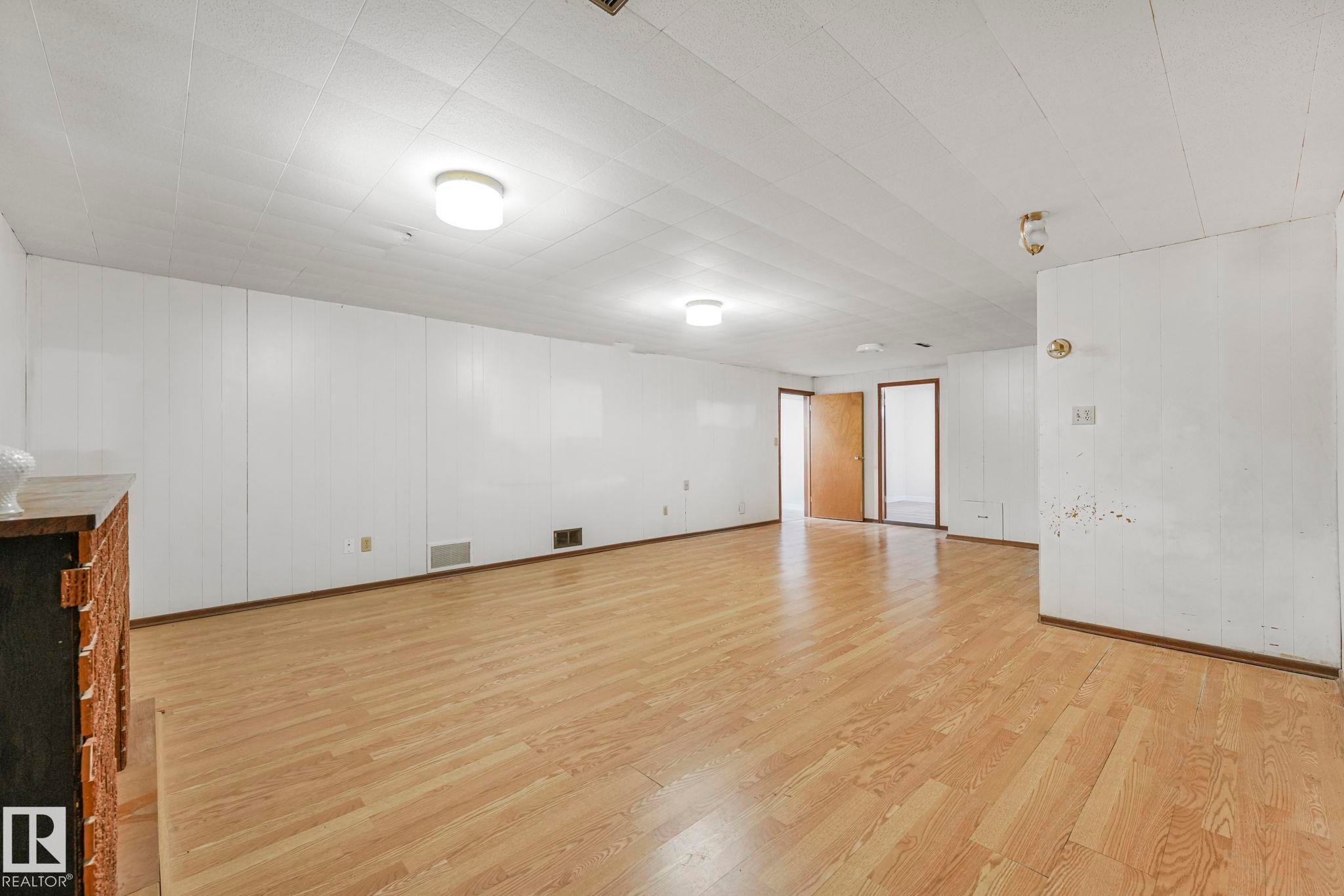 Empty room featuring light wood finished floors and wooden walls - 6007 95 Avenue, Edmonton, AB - Indoor Photo Showing Other Room