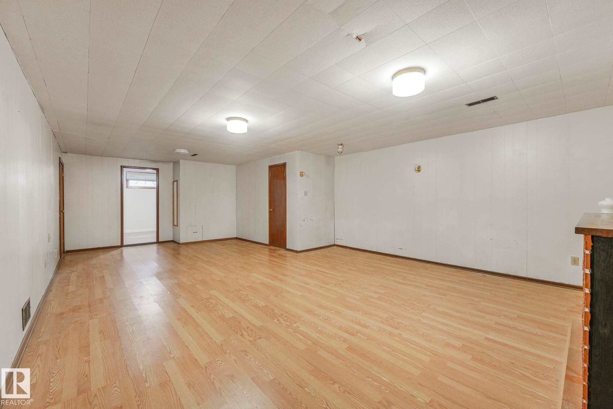 Empty room with light wood finished floors and wooden walls - 6007 95 Avenue, Edmonton, AB - Indoor Photo Showing Other Room