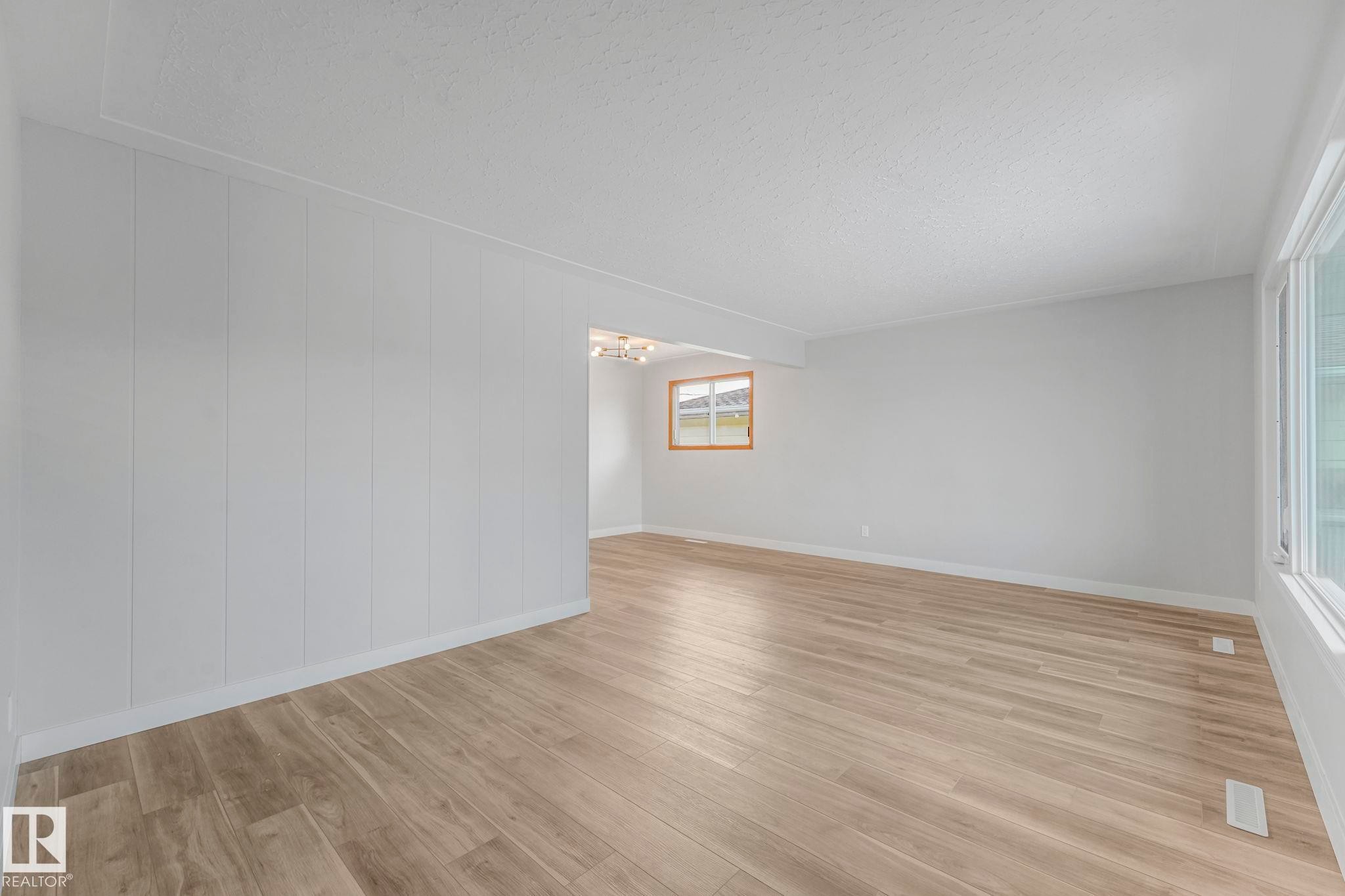 Unfurnished room with light wood finished floors, a textured ceiling, and hanging lights - 6007 95 Avenue, Edmonton, AB - Indoor Photo Showing Other Room