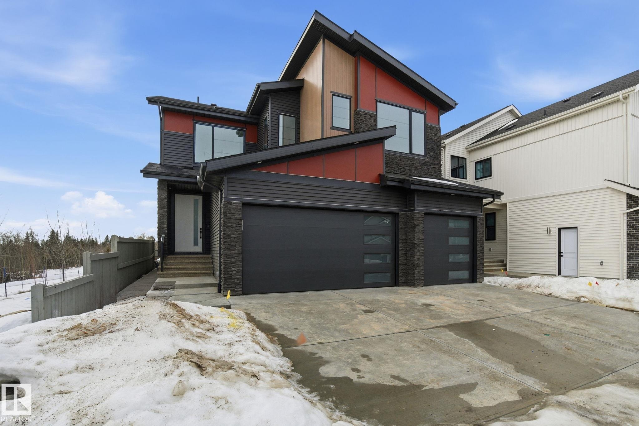 Contemporary house featuring stone siding, driveway, an attached garage, and board and batten siding - 17108 2 Street, Edmonton, AB - Outdoor