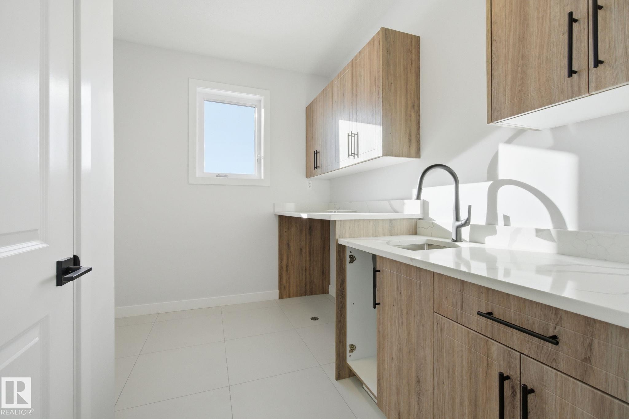 Laundry area featuring baseboards and light tile patterned floors - 17108 2 Street, Edmonton, AB - Indoor