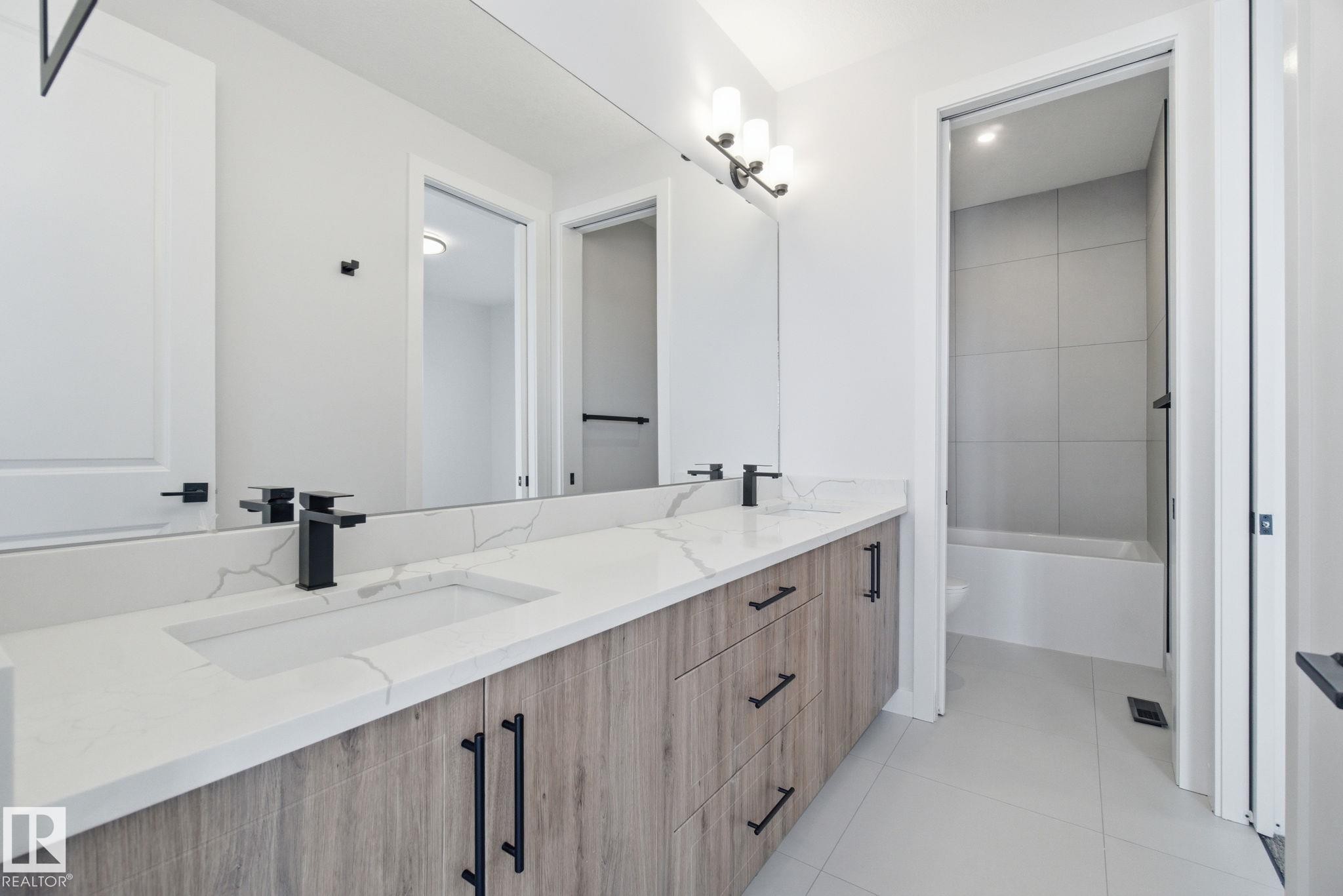 Bathroom featuring double vanity, light tile patterned flooring, and shower / bathtub combination - 17108 2 Street, Edmonton, AB - Indoor Photo Showing Bathroom
