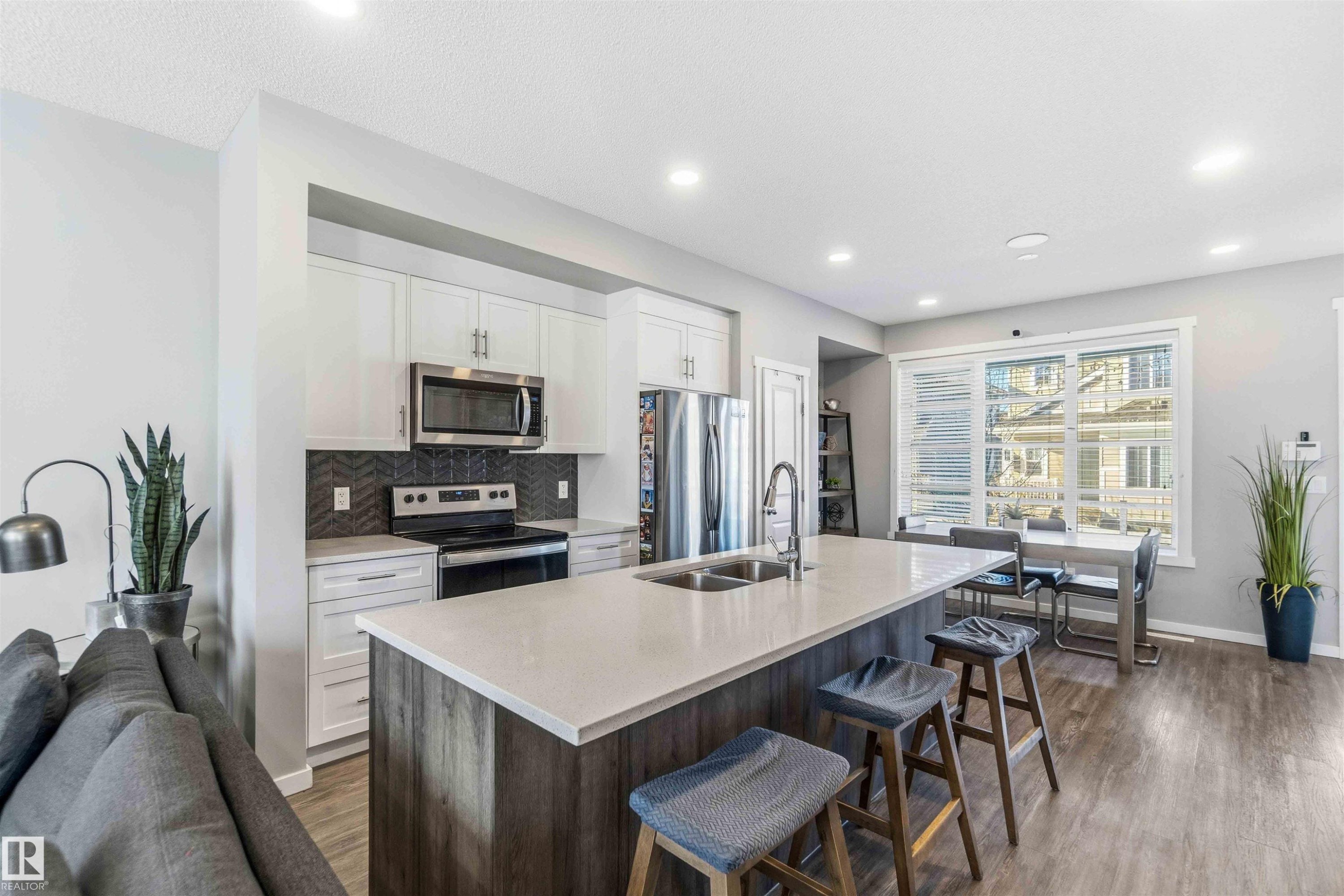 Kitchen featuring stainless steel appliances, a kitchen island with sink, a breakfast bar area, open floor plan, and light stone countertops - 1908 25 Street, Edmonton, AB - Indoor Photo Showing Kitchen With Stainless Steel Kitchen With Double Sink With Upgraded Kitchen