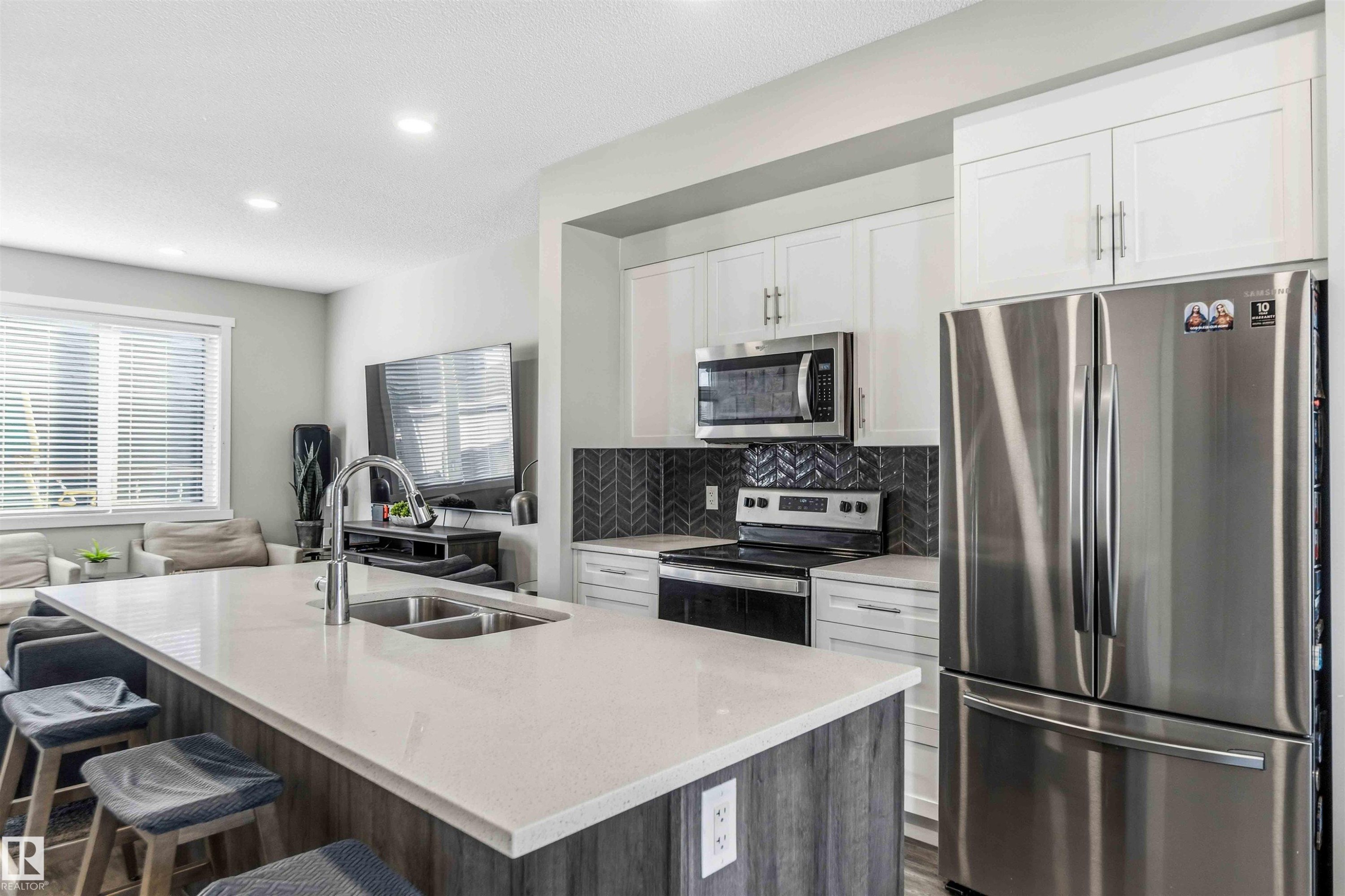 Dual tone kitchen with stainless steel appliances, open floor plan, light stone counters, decorative backsplash, and an island with sink - 1908 25 Street, Edmonton, AB - Indoor Photo Showing Kitchen With Stainless Steel Kitchen With Double Sink With Upgraded Kitchen