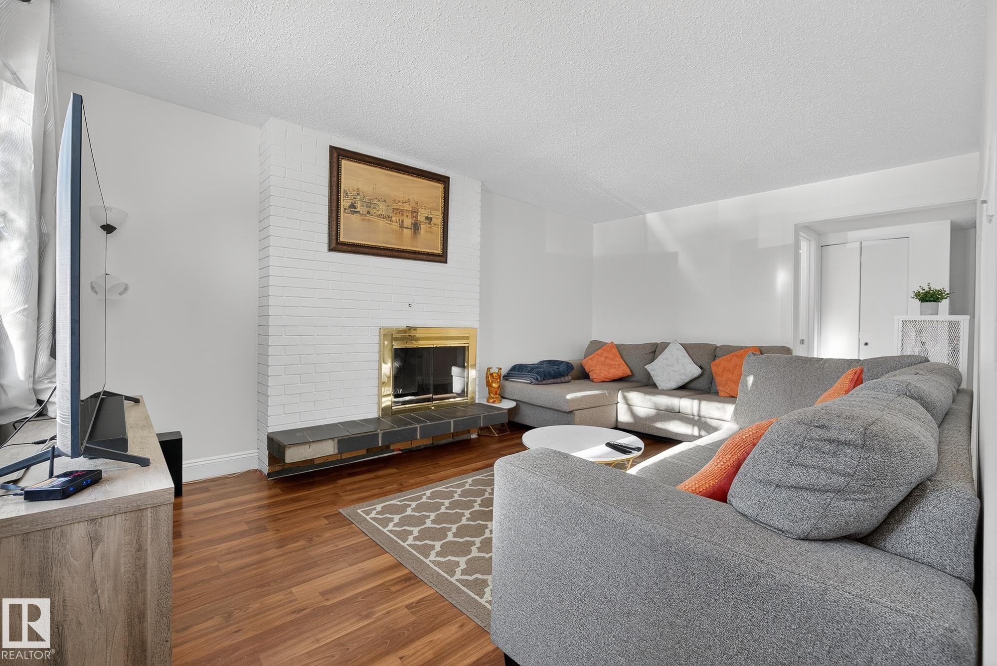 Living area featuring a tile fireplace, wood finished floors, and a textured ceiling - 10602 66 Avenue, Edmonton, AB - Indoor Photo Showing Living Room With Fireplace
