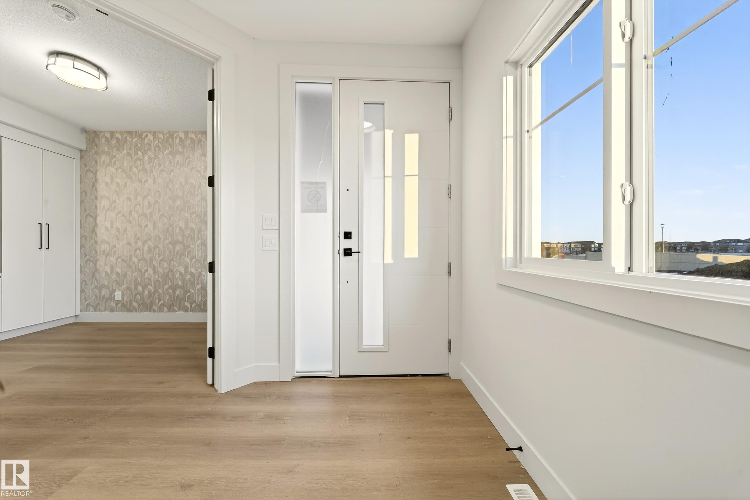 Entryway featuring light wood-style floors, healthy amount of natural light, and wallpapered walls - 8924 Mayday Way, Edmonton, AB