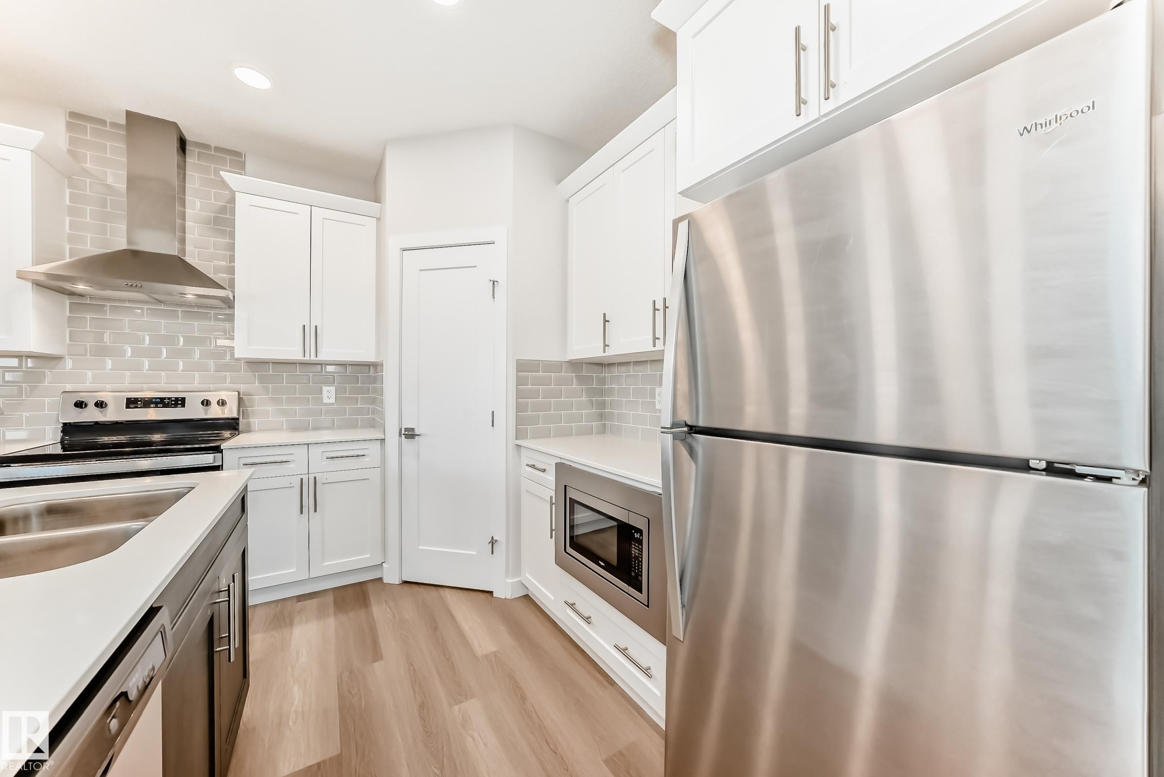 Kitchen featuring stainless steel appliances, light wood-style flooring, recessed lighting, light stone counters, and dual tone cabinets - 17926 62A Street, Edmonton, AB - Indoor Photo Showing Kitchen With Double Sink With Upgraded Kitchen