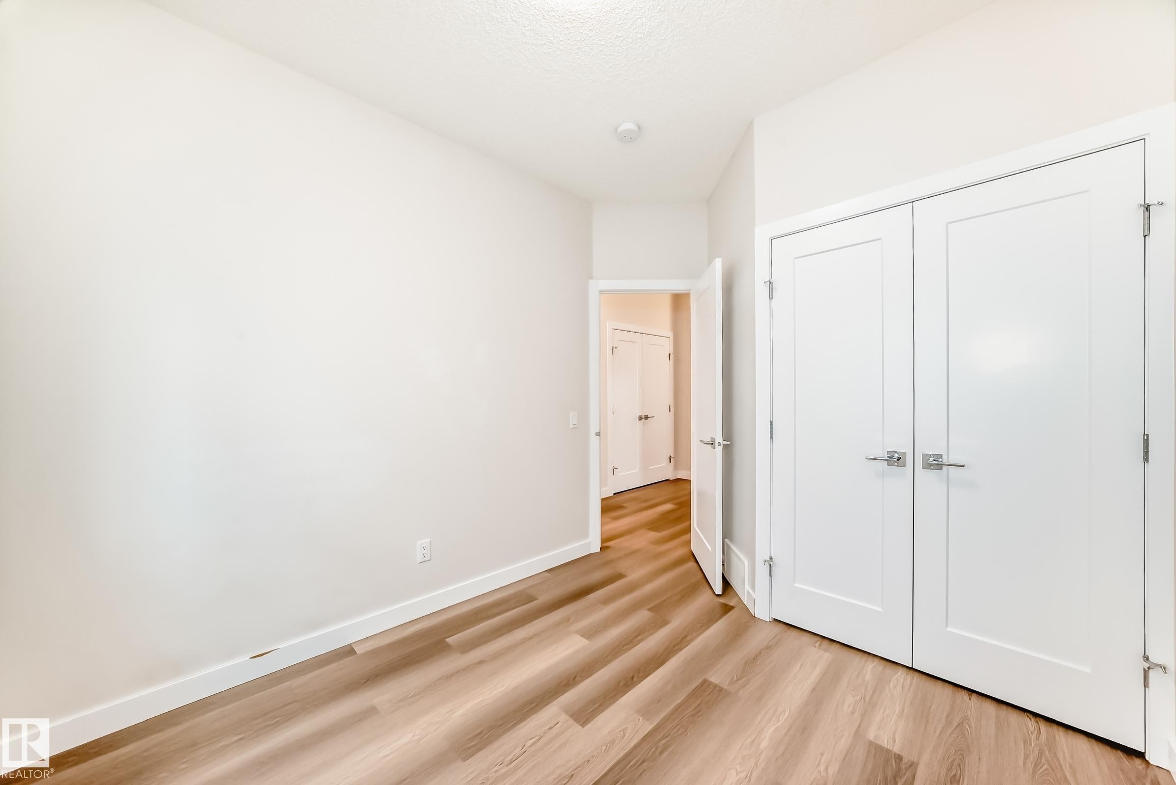 Unfurnished bedroom featuring light wood-style flooring, a closet, and a textured ceiling - 17926 62A Street, Edmonton, AB - Indoor Photo Showing Other Room