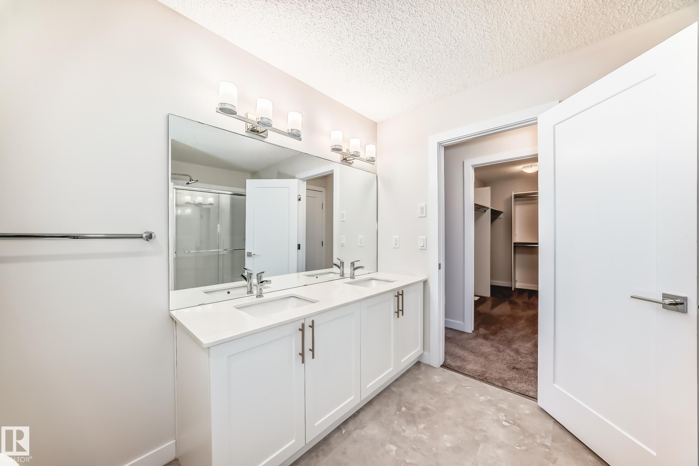 Bathroom with a stall shower, double vanity, a spacious closet, a textured ceiling, and unfinished concrete flooring - 17926 62A Street, Edmonton, AB - Indoor