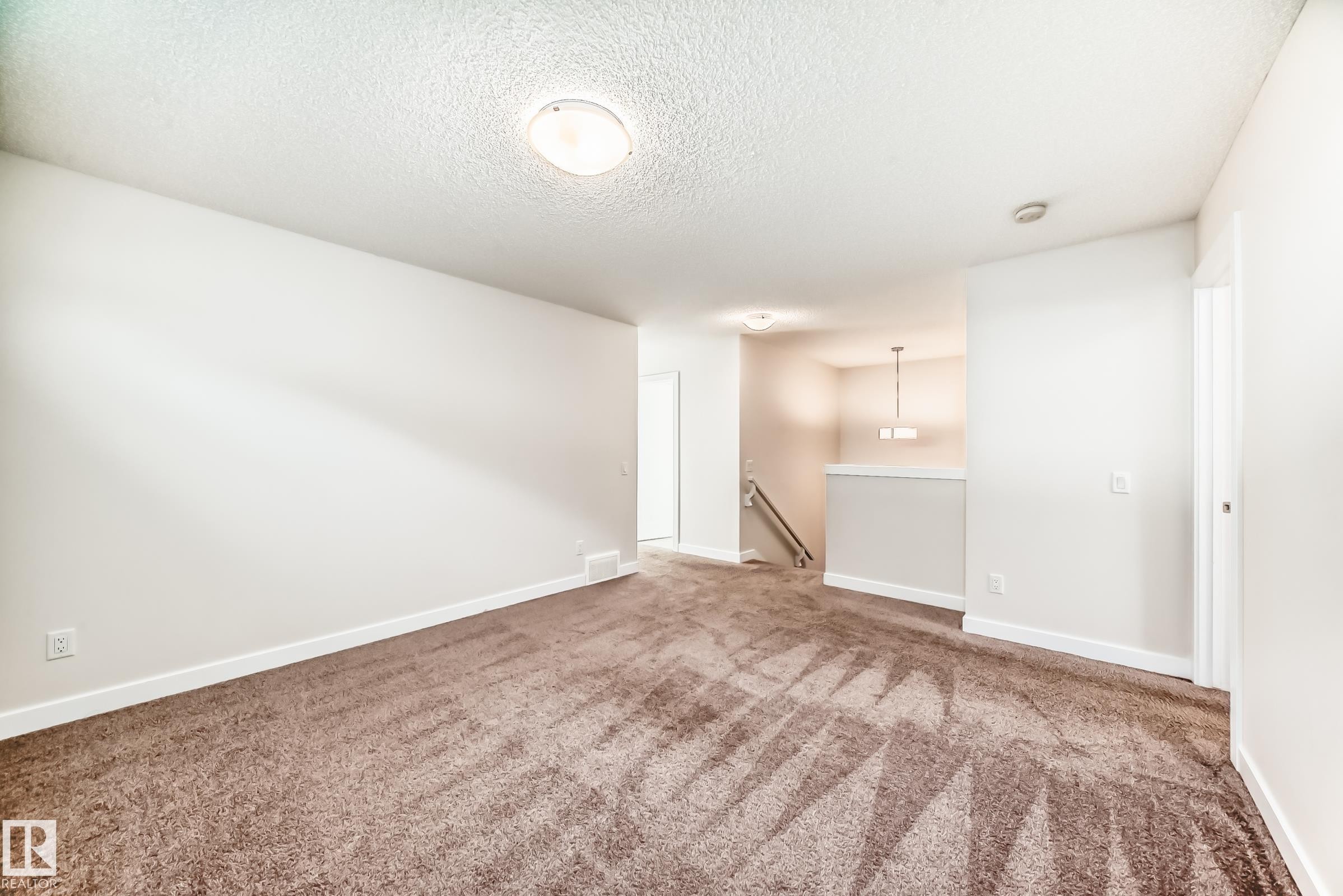 Carpeted empty room featuring a textured ceiling and baseboards - 17926 62A Street, Edmonton, AB - Indoor Photo Showing Other Room
