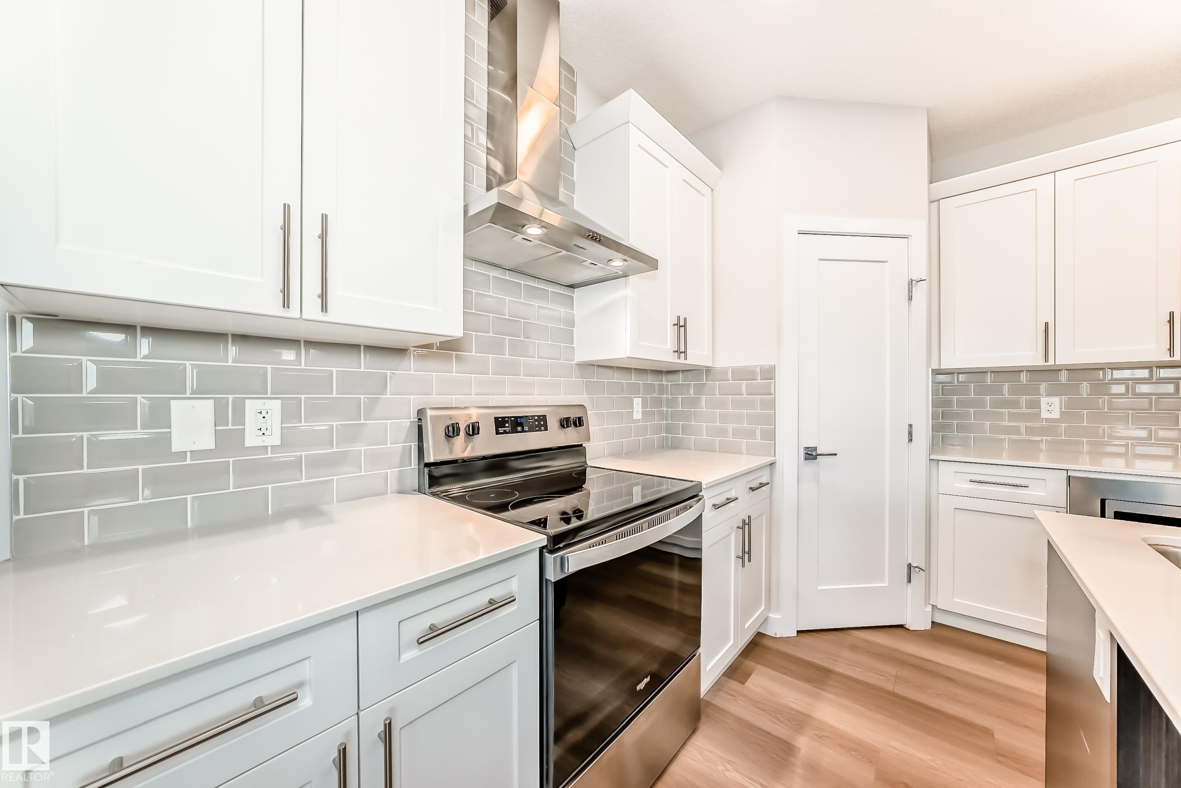 Kitchen with stainless steel range with electric stovetop, white cabinets, and light wood-type flooring - 17926 62A Street, Edmonton, AB - Indoor Photo Showing Kitchen With Upgraded Kitchen