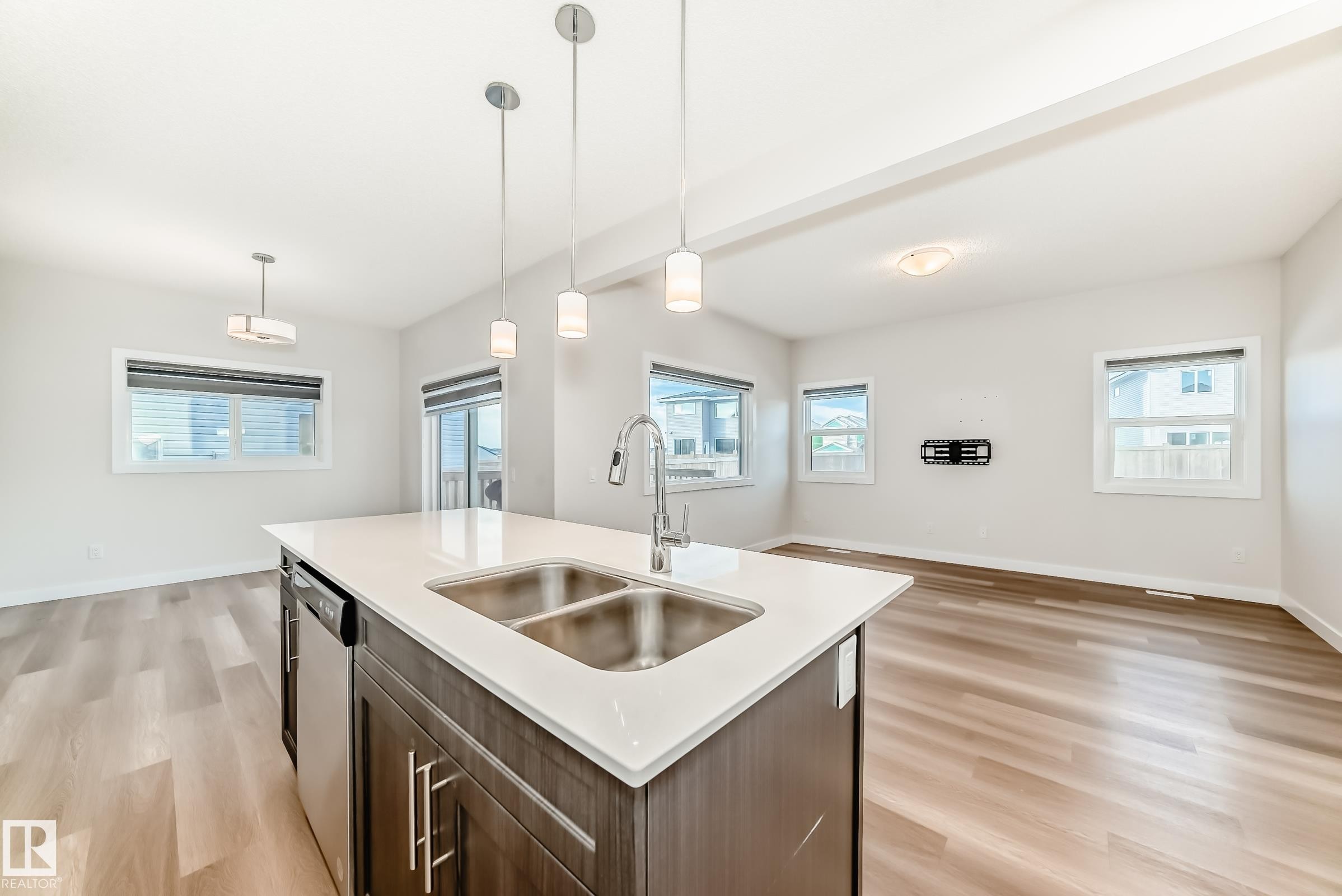 Kitchen featuring pendant lighting, light wood-style floors, plenty of natural light, and beamed ceiling - 17926 62A Street, Edmonton, AB - Indoor Photo Showing Kitchen With Double Sink