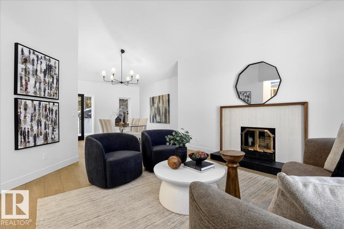 Living room with wood finished floors, a chandelier, and a fireplace - 218 Omand Drive, Edmonton, AB - Indoor Photo Showing Living Room With Fireplace