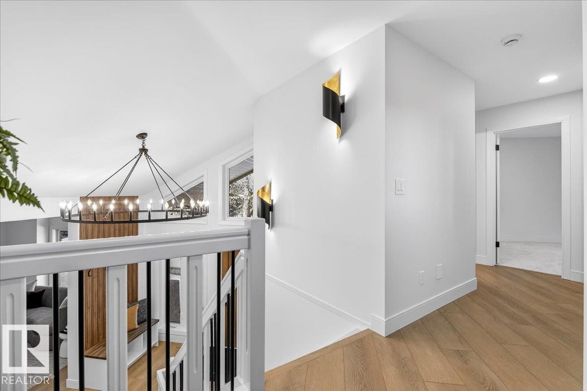 Hallway with light wood-style floors, suspended lighting, and an upstairs landing - 218 Omand Drive, Edmonton, AB - Indoor Photo Showing Other Room