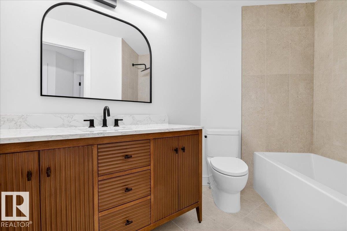 Bathroom featuring vanity, light tile patterned floors, tile walls, and shower / tub combination - 218 Omand Drive, Edmonton, AB - Indoor Photo Showing Bathroom