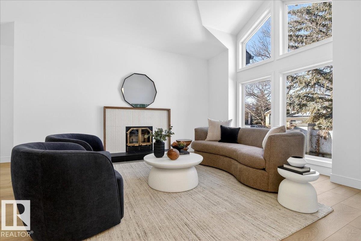 Living room with light wood-style flooring, a tiled fireplace, and a high ceiling - 218 Omand Drive, Edmonton, AB - Indoor Photo Showing Living Room With Fireplace
