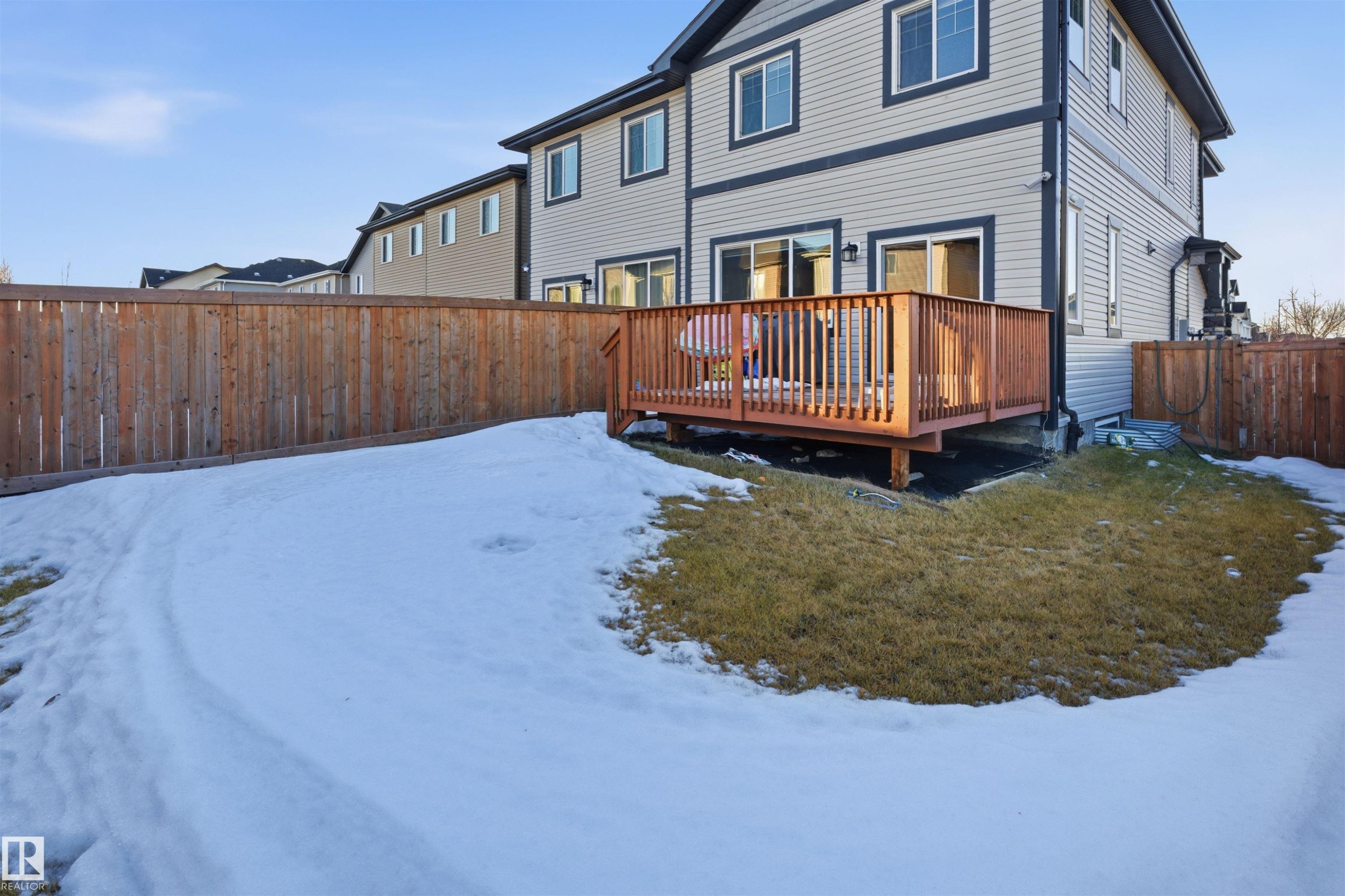 Snow covered back of property featuring a fenced backyard and a wooden deck - 5003 Andison Close, Edmonton, AB - Outdoor