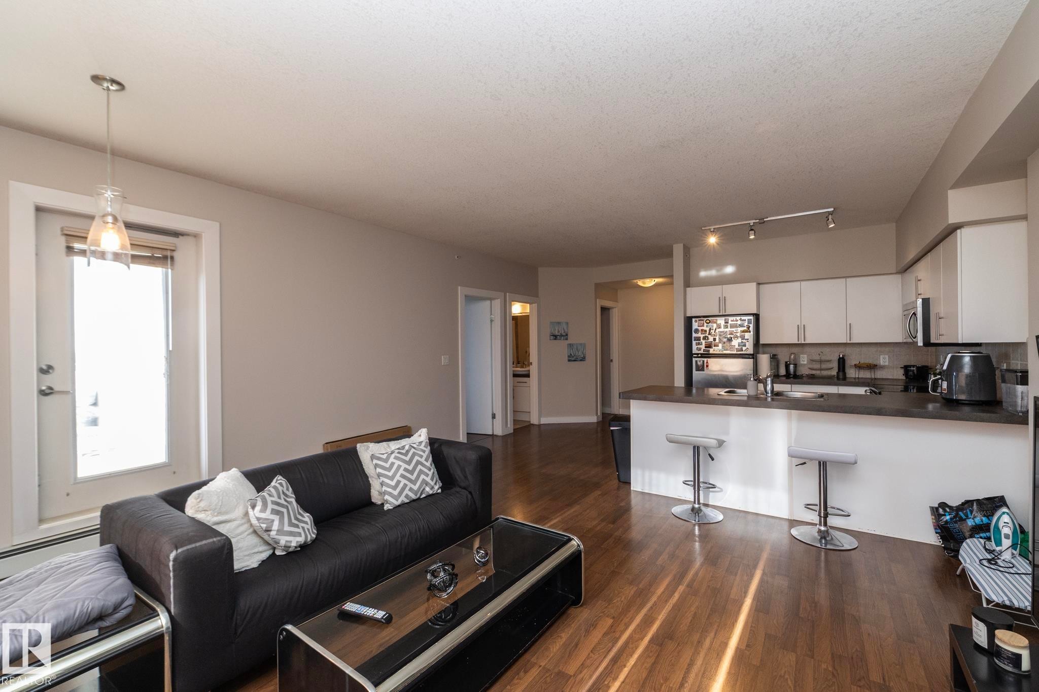 Living room featuring dark wood-type flooring and a baseboard heating unit - 2005 10136 104 Street, Edmonton, AB - Indoor