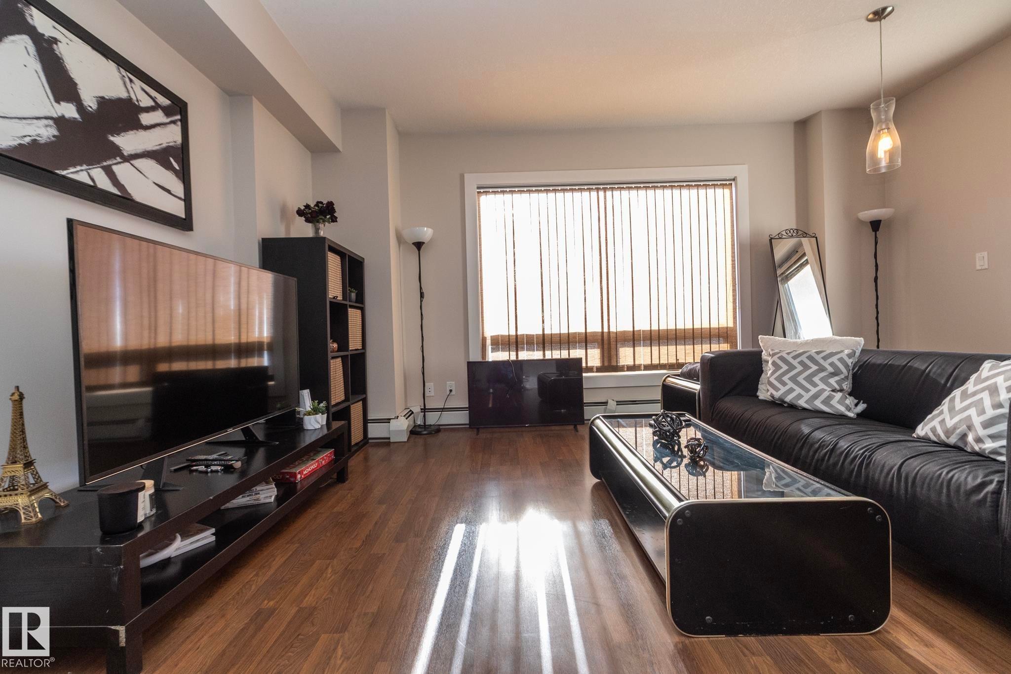 Living room featuring dark wood finished floors and baseboard heating - 2005 10136 104 Street, Edmonton, AB - Indoor Photo Showing Living Room