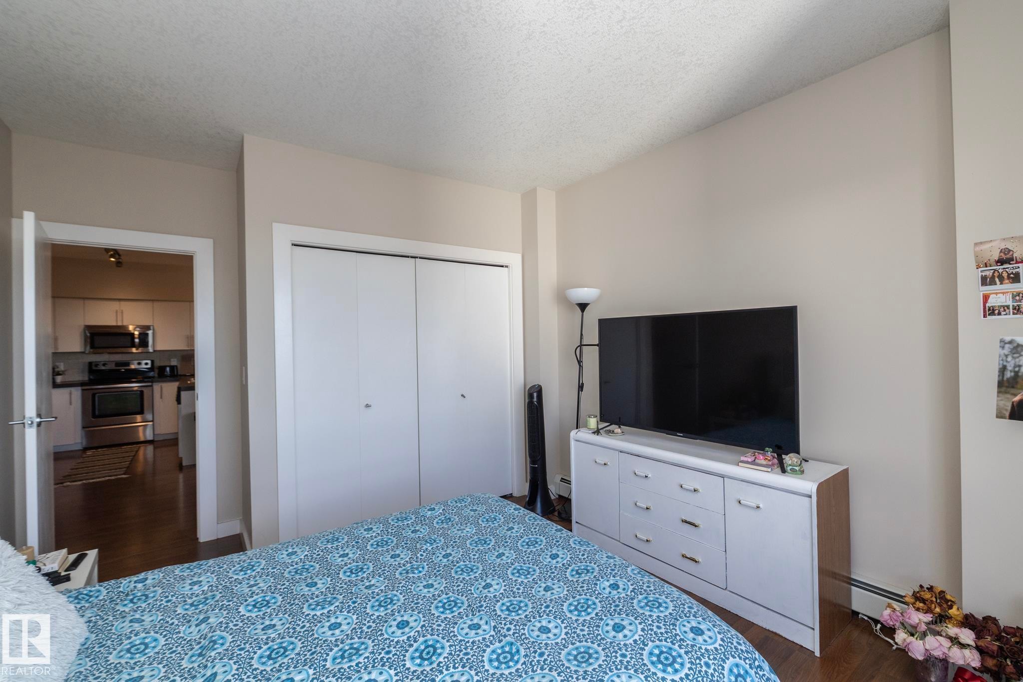 Bedroom with dark wood finished floors, a textured ceiling, a closet, and baseboard heating - 2005 10136 104 Street, Edmonton, AB - Indoor Photo Showing Bedroom