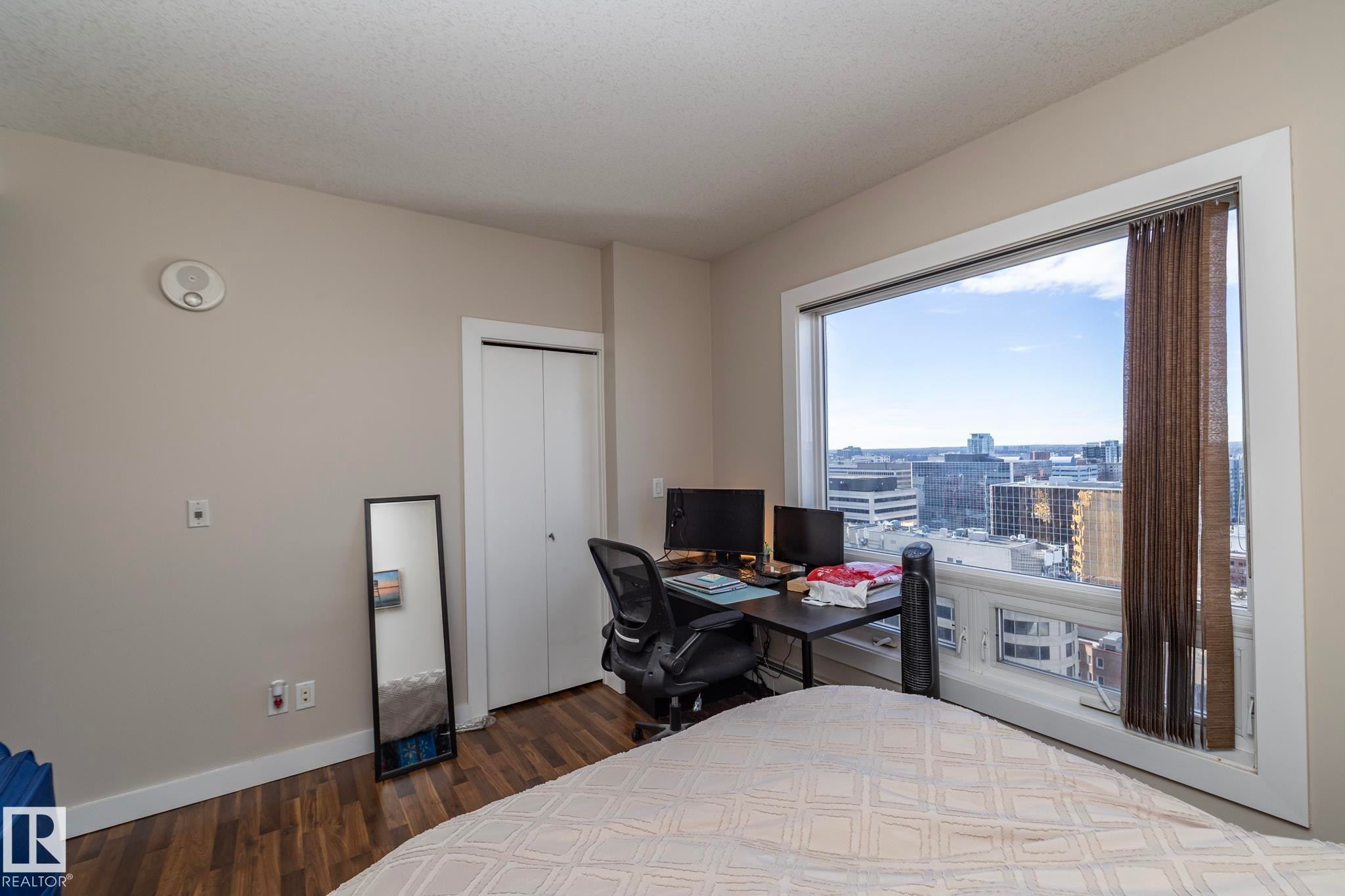 Bedroom with a desk, dark wood-type flooring, and a closet - 2005 10136 104 Street, Edmonton, AB - Indoor Photo Showing Bedroom