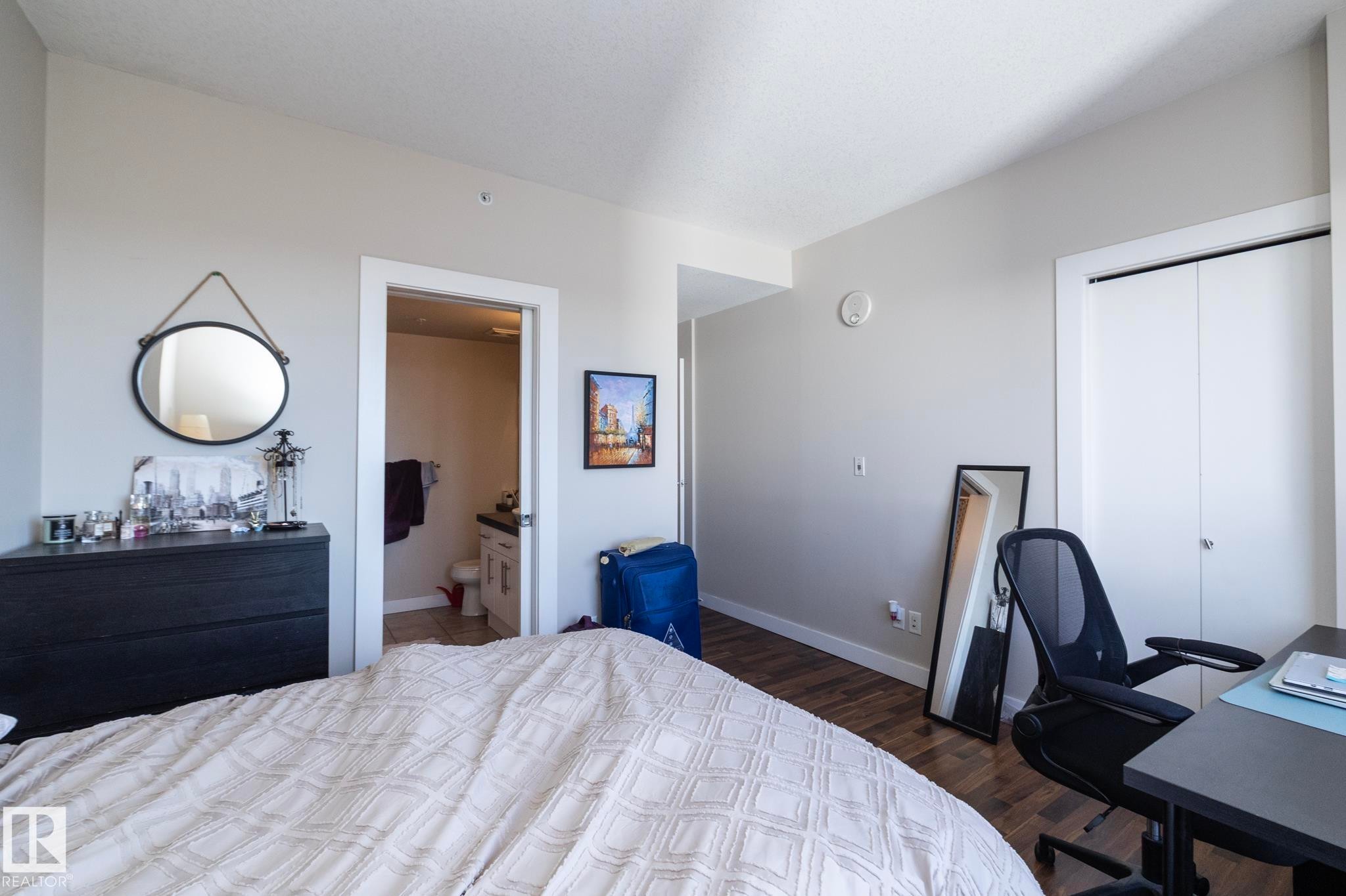 Bedroom featuring a desk, dark wood-type flooring, a closet, and ensuite bathroom - 2005 10136 104 Street, Edmonton, AB - Indoor Photo Showing Bedroom