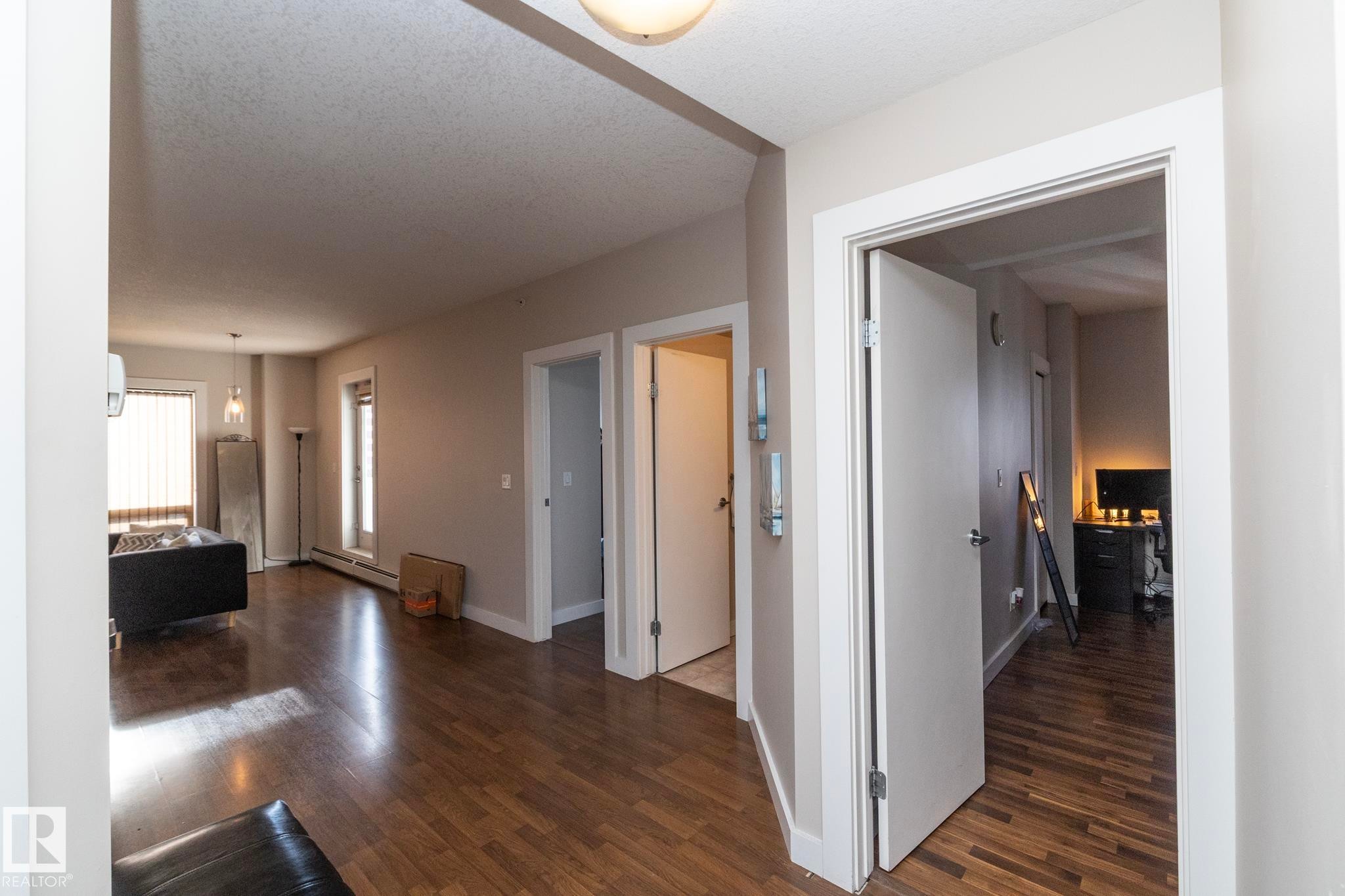 Corridor featuring dark wood-style flooring, baseboard heating, and a textured ceiling - 2005 10136 104 Street, Edmonton, AB - Indoor Photo Showing Other Room