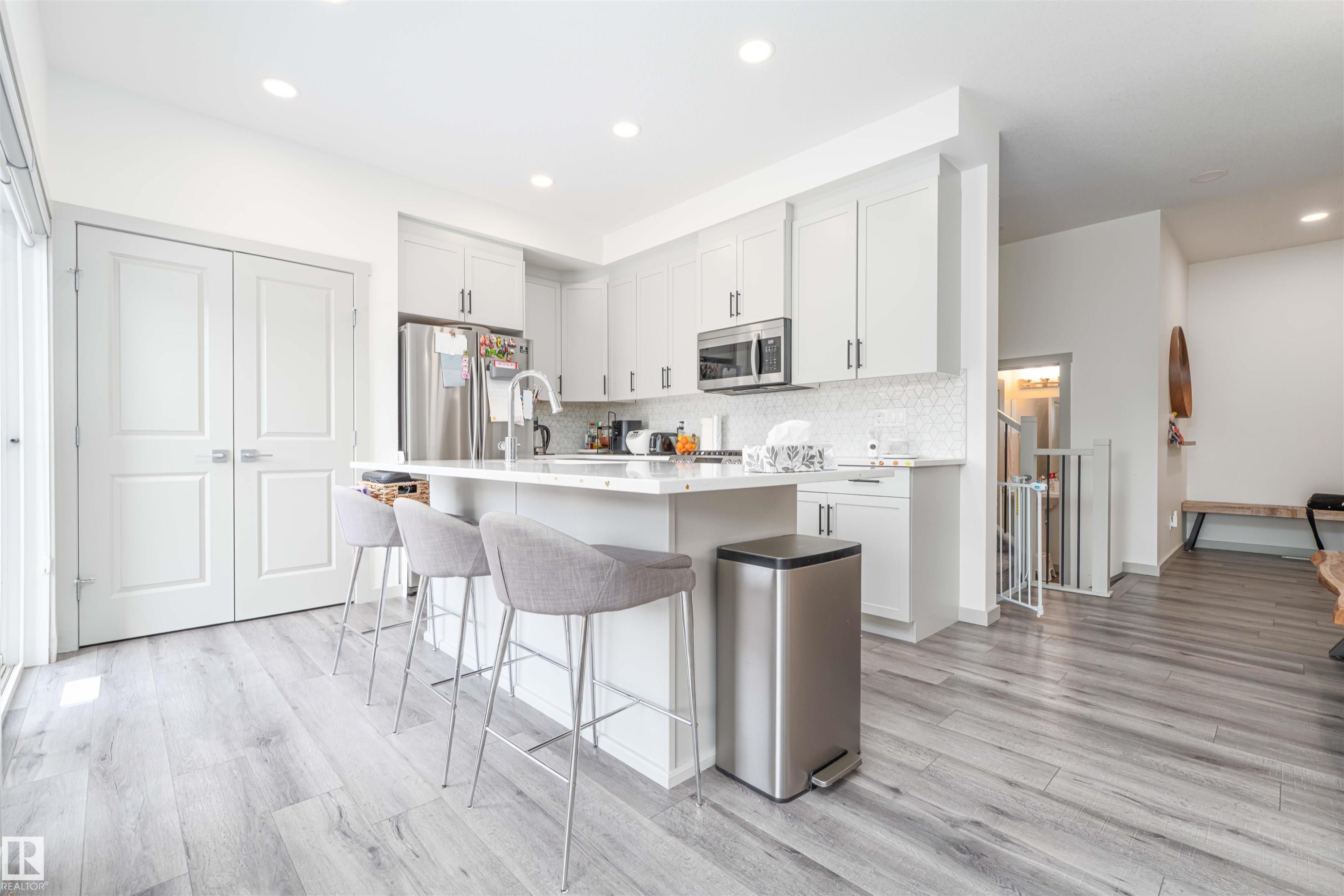 Kitchen with a kitchen island with sink, light wood finished floors, a breakfast bar area, stainless steel appliances, and recessed lighting - 2330 Kelly Circle, Edmonton, AB - Indoor Photo Showing Kitchen With Upgraded Kitchen