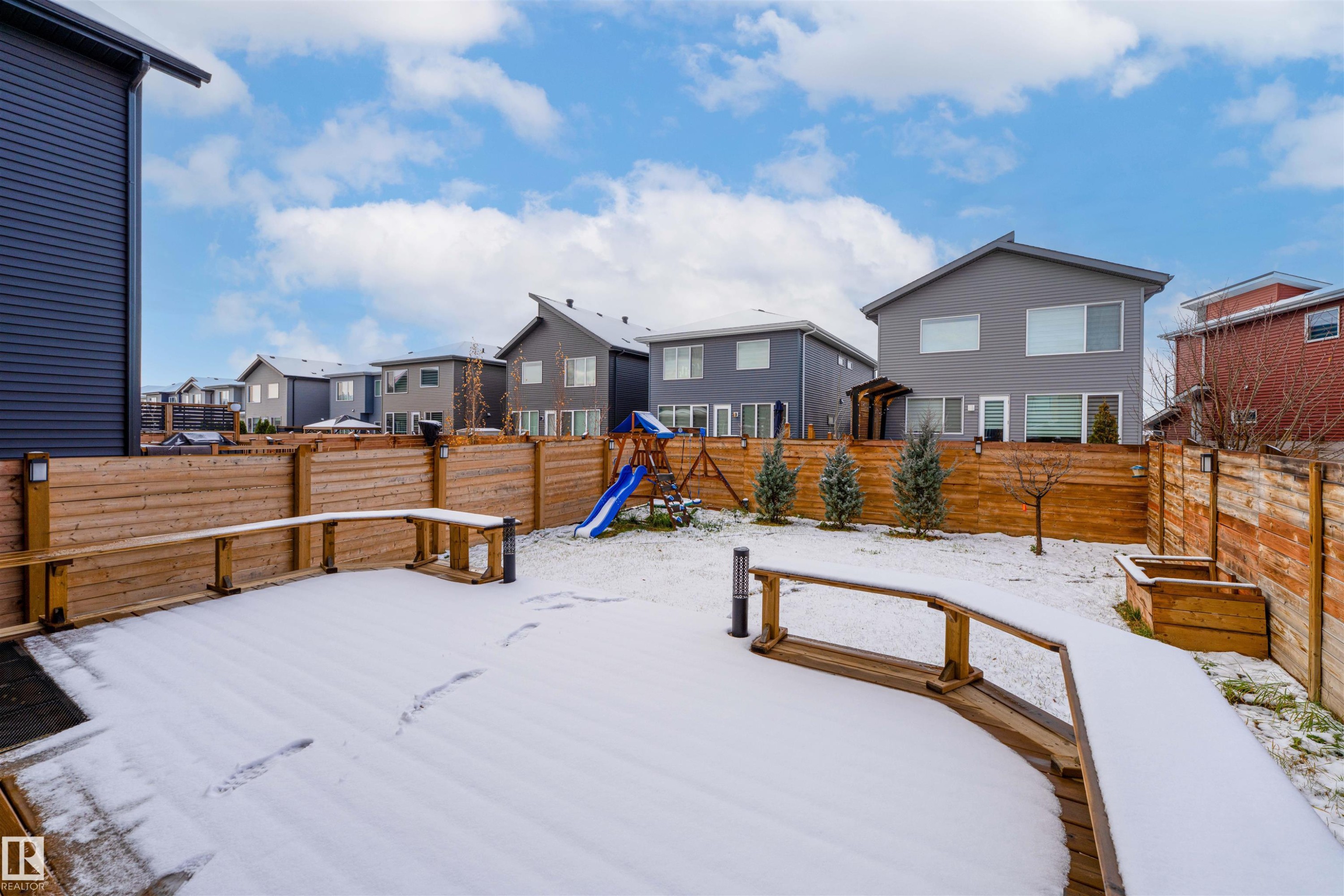 Yard layered in snow featuring a residential view, a fenced backyard, a playground, and a deck - 2330 Kelly Circle, Edmonton, AB - Outdoor With Deck Patio Veranda With Exterior