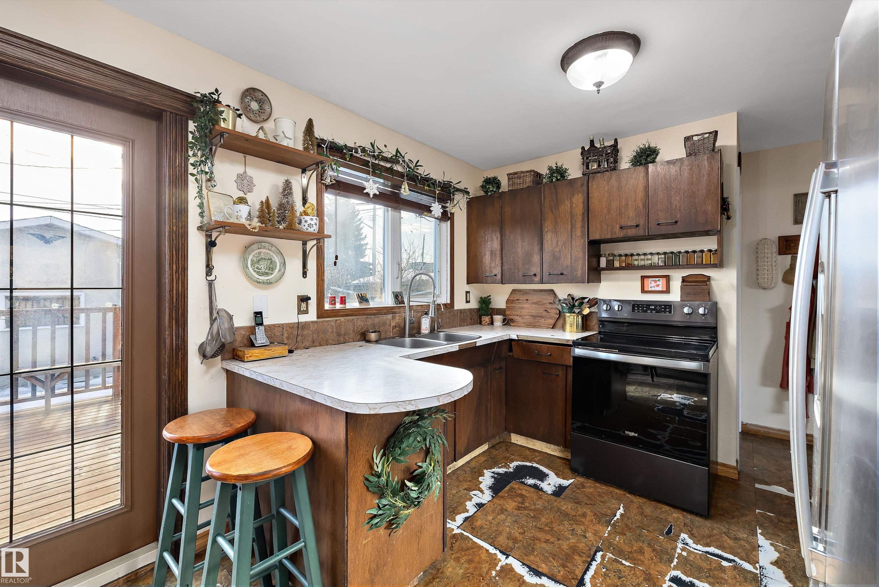 Kitchen with stainless steel appliances, dark wood finish cabinets, light countertops, and open shelves - 5703 143 Avenue, Edmonton, AB - Indoor Photo Showing Kitchen With Double Sink