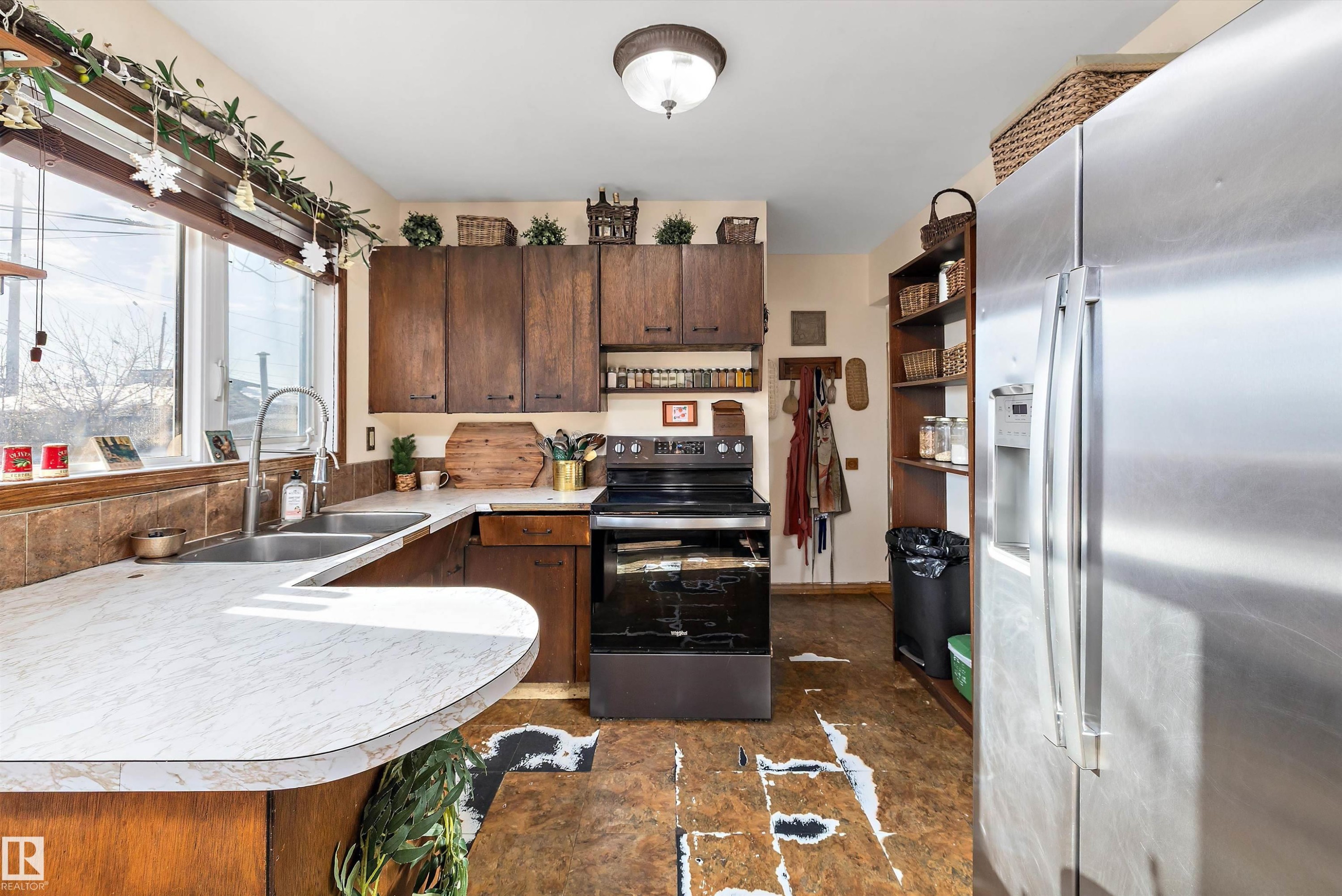 Kitchen with stainless steel appliances, light countertops, dark wood finish cabinetry, and a peninsula - 5703 143 Avenue, Edmonton, AB - Indoor Photo Showing Kitchen With Double Sink