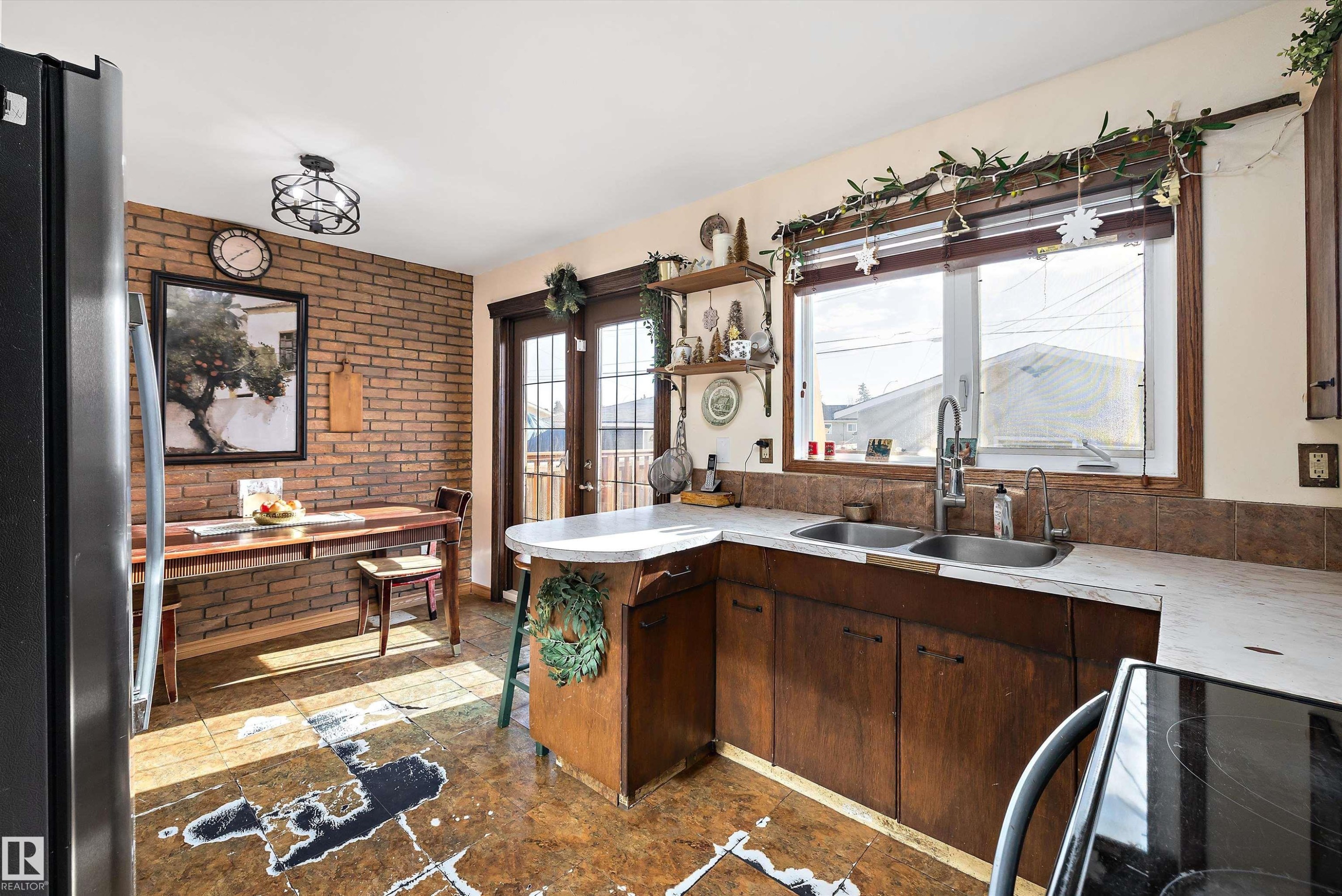 Kitchen featuring freestanding refrigerator, brick wall, electric range, light countertops, and french doors - 5703 143 Avenue, Edmonton, AB - Indoor Photo Showing Kitchen With Double Sink