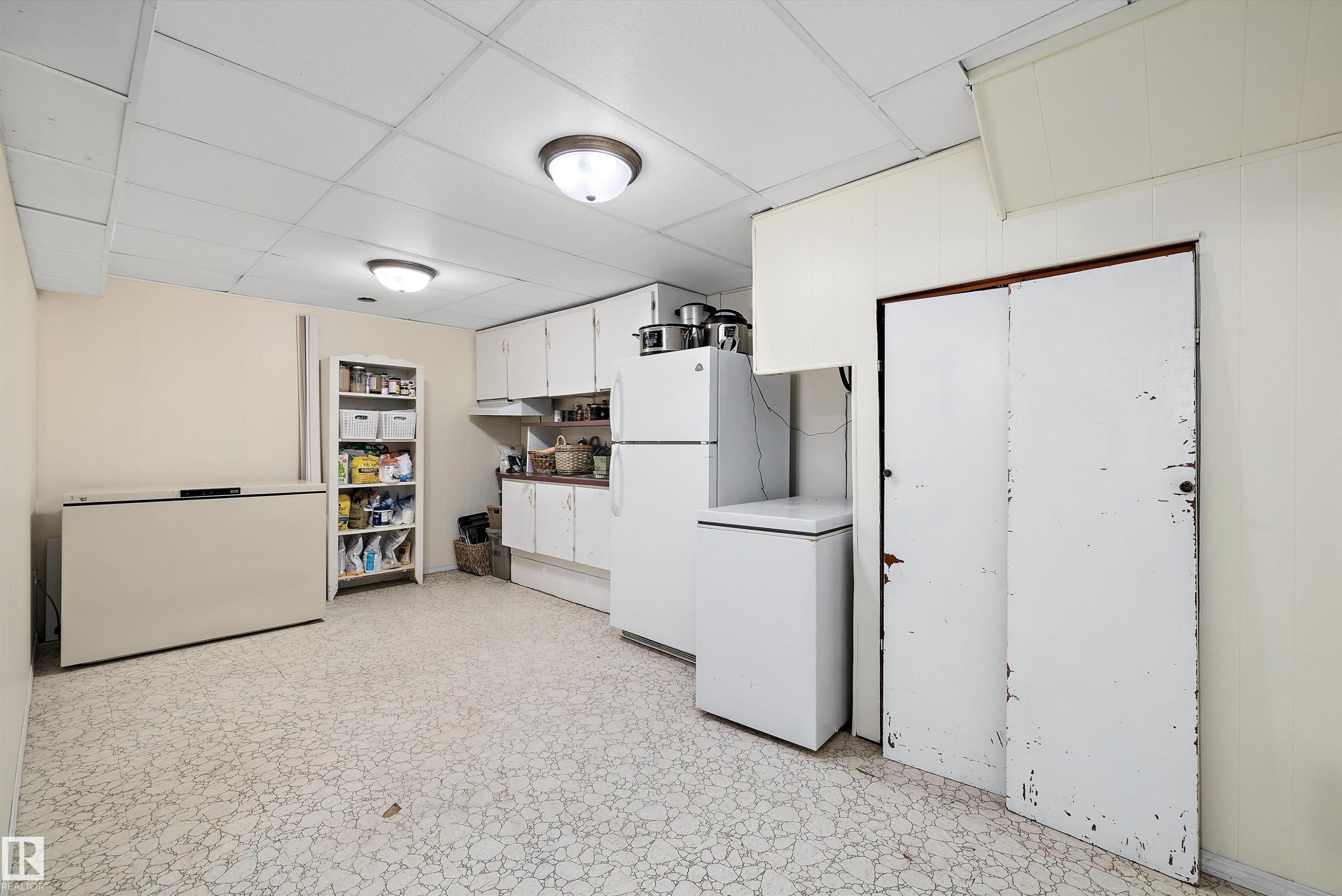 Kitchen with white cabinets, freestanding refrigerator, a drop ceiling, light countertops, and light floors - 5703 143 Avenue, Edmonton, AB - Indoor