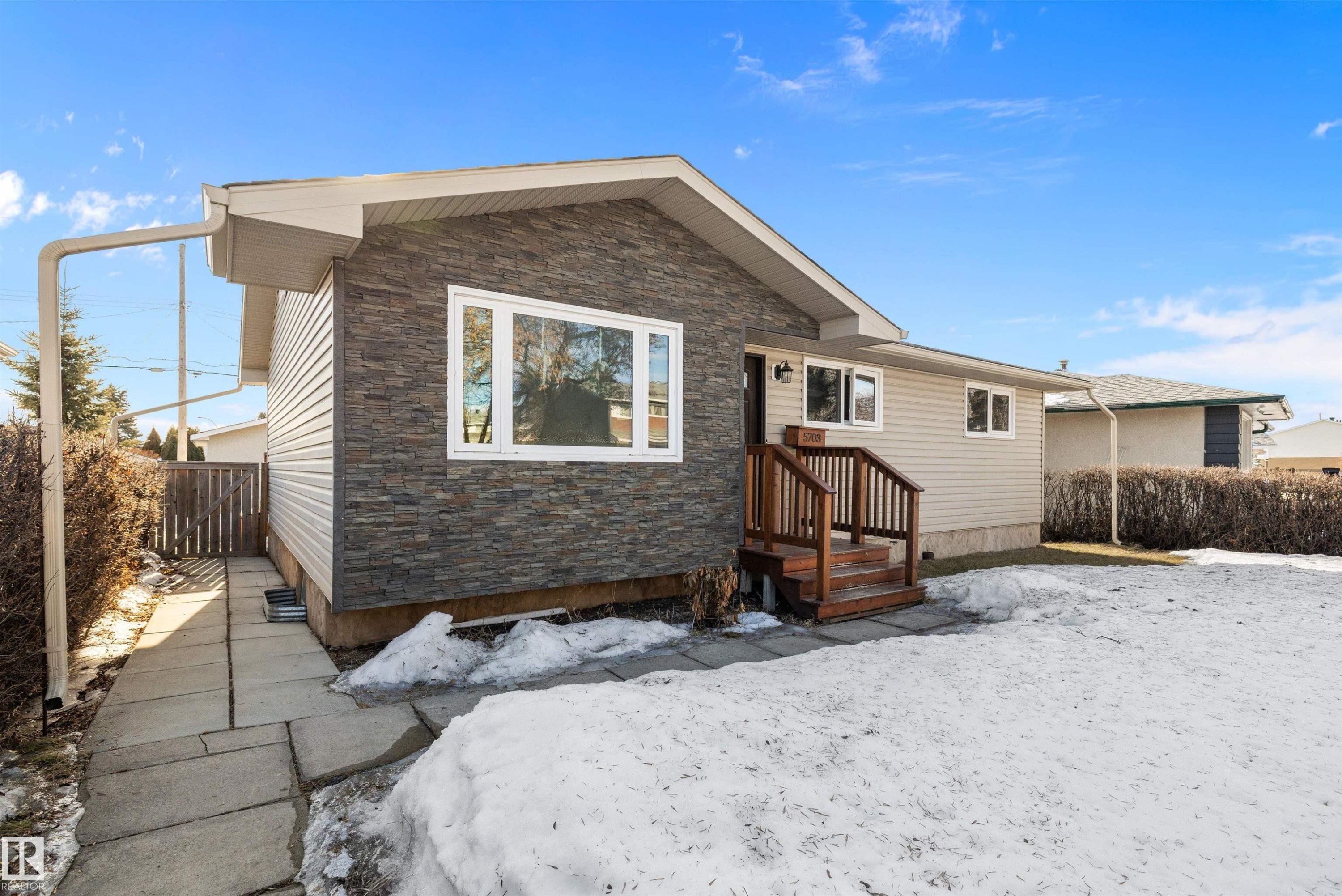 Snow covered property featuring stone siding - 5703 143 Avenue, Edmonton, AB - Outdoor With Exterior