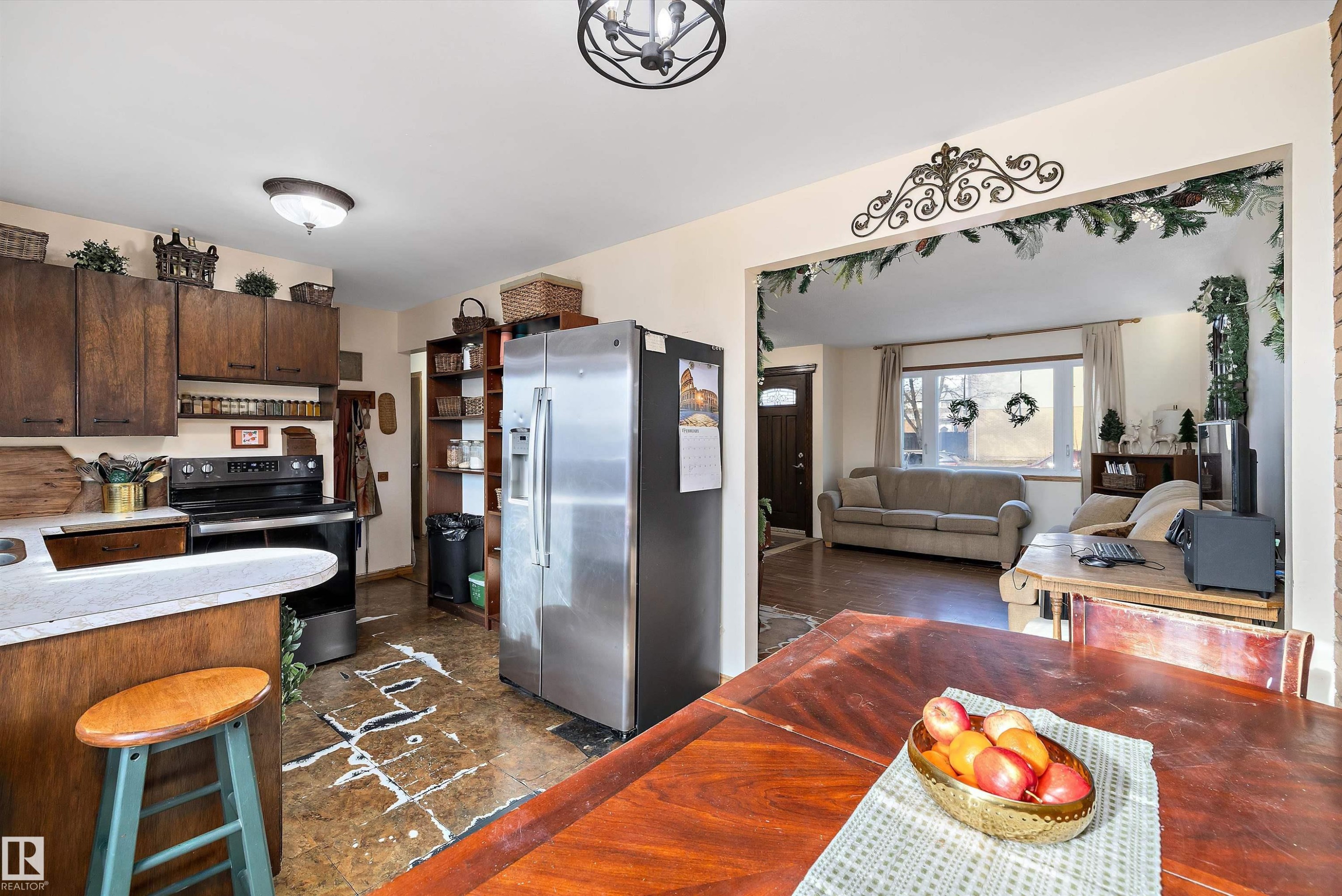 Kitchen featuring stainless steel fridge, range with electric cooktop, light countertops, dark wood finish cabinets, and open floor plan - 5703 143 Avenue, Edmonton, AB - Indoor