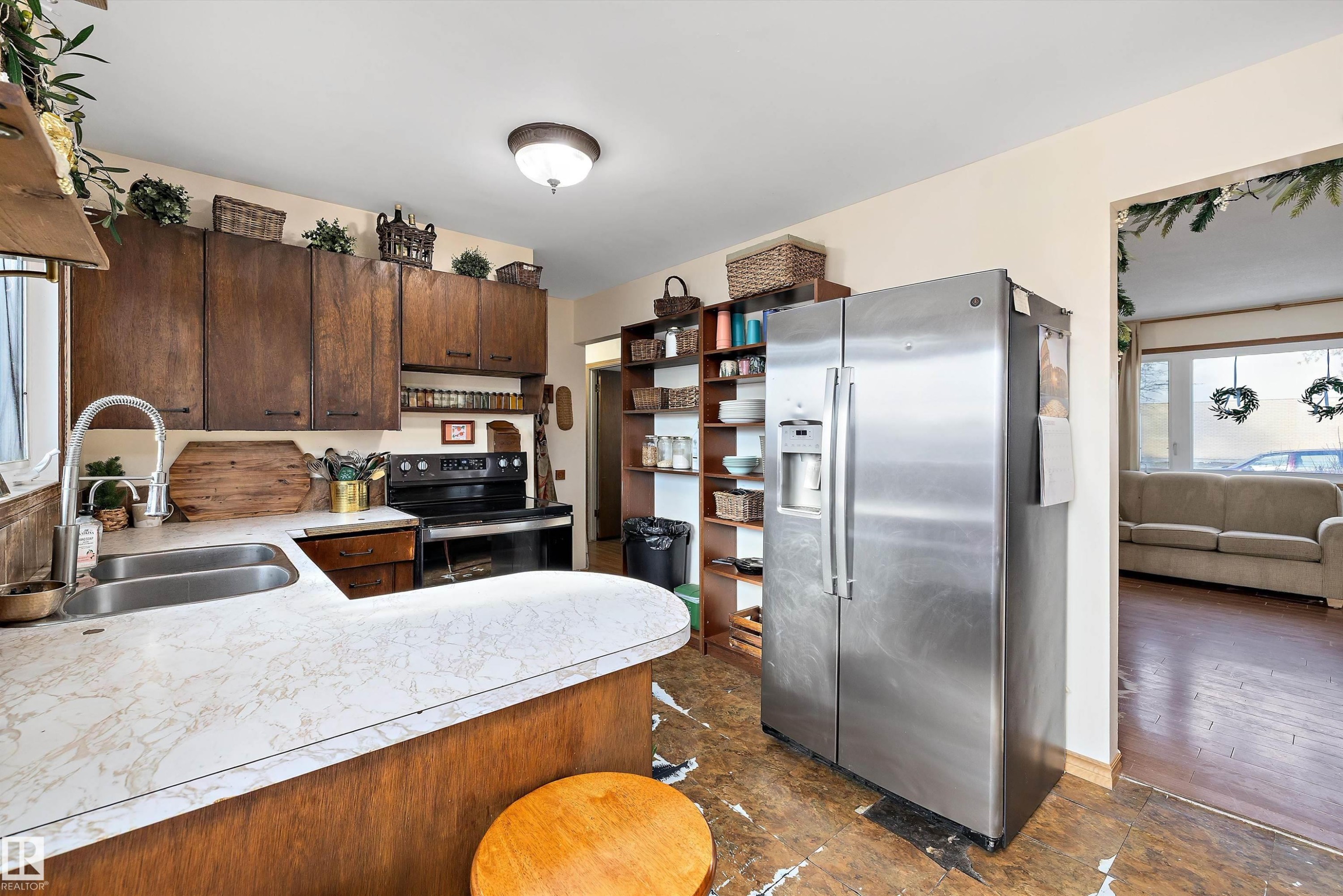 Kitchen with stainless steel fridge with ice dispenser, range with electric stovetop, light countertops, dark wood finish cabinets, and a peninsula - 5703 143 Avenue, Edmonton, AB - Indoor Photo Showing Kitchen With Double Sink