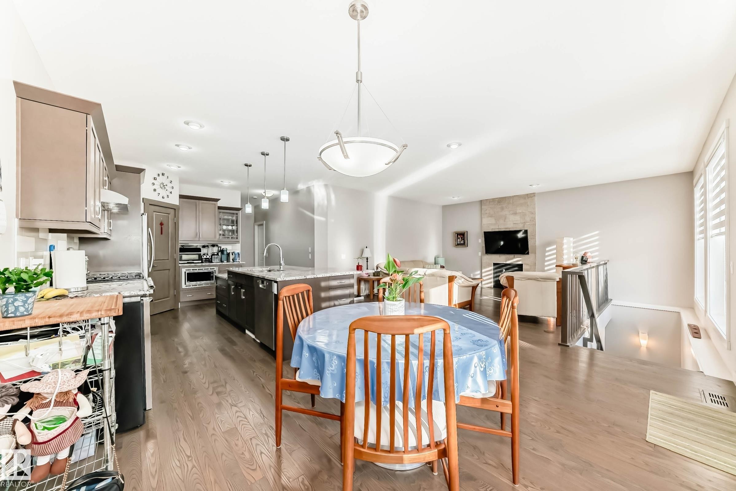 Dining room with light wood-style flooring, recessed lighting, and a large fireplace - 7719 Getty Wynd, Edmonton, AB - Indoor Photo Showing Dining Room