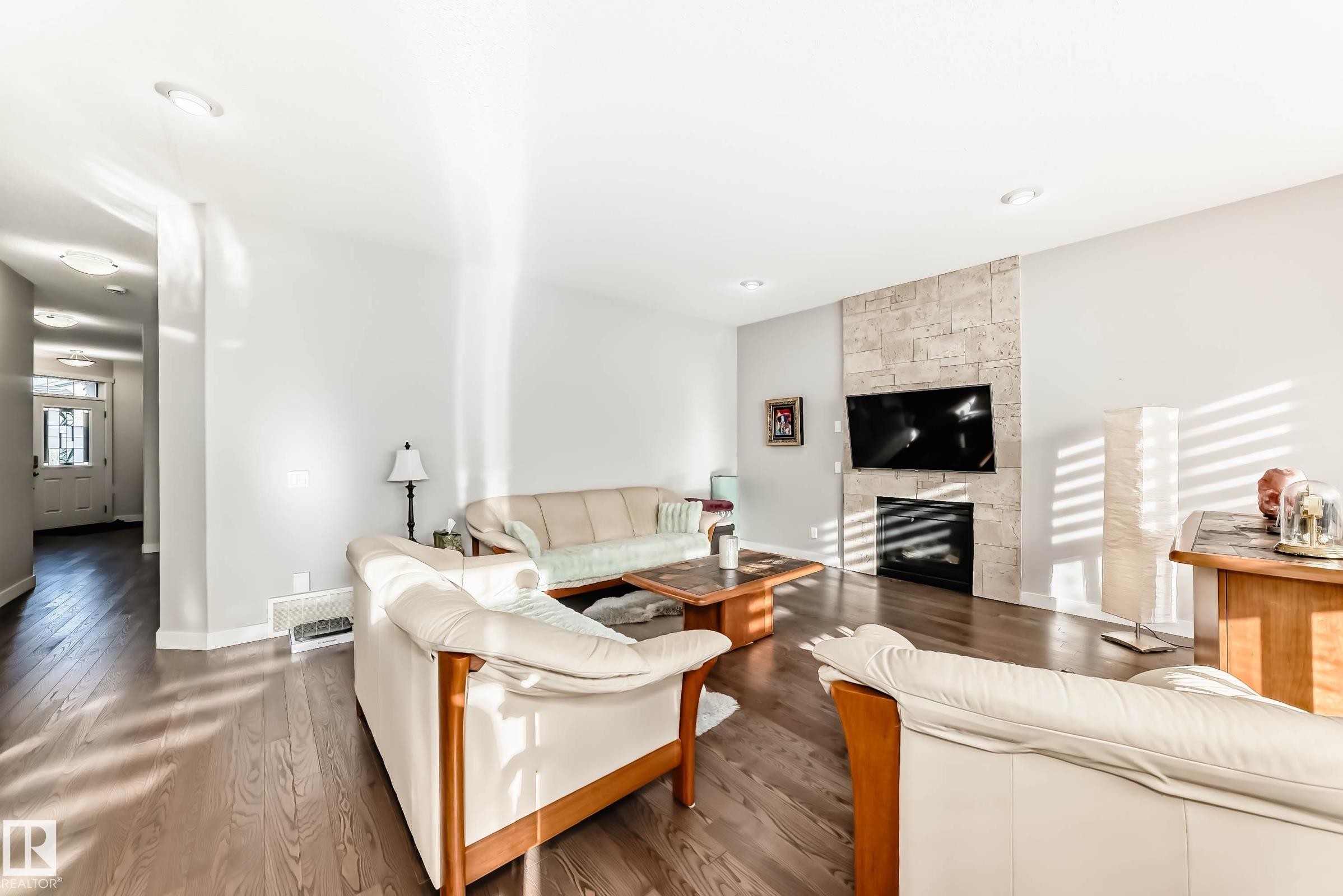 Living area with dark wood-style flooring and a large fireplace - 7719 Getty Wynd, Edmonton, AB - Indoor Photo Showing Living Room With Fireplace