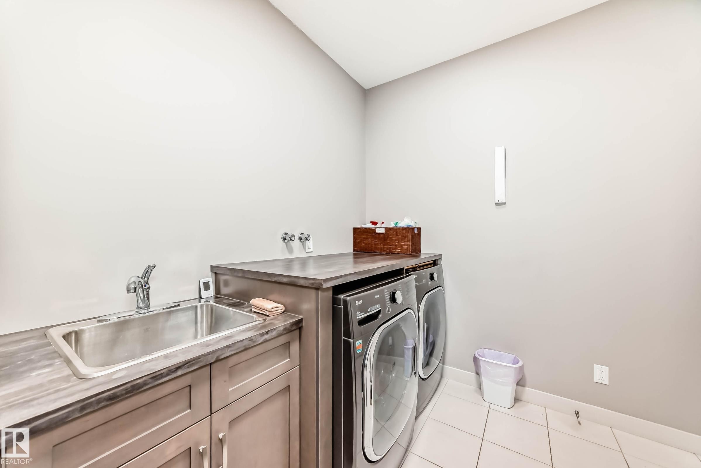 Laundry room featuring light tile patterned floors, washing machine and dryer, and cabinet space - 7719 Getty Wynd, Edmonton, AB - Indoor Photo Showing Laundry Room