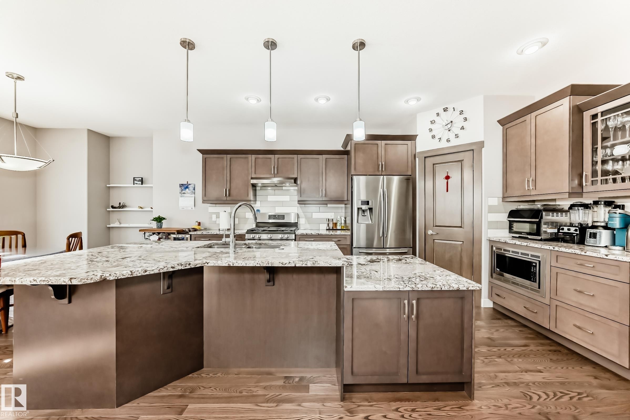 Kitchen with light stone counters, stainless steel appliances, and decorative light fixtures - 7719 Getty Wynd, Edmonton, AB - Indoor Photo Showing Kitchen With Double Sink With Upgraded Kitchen