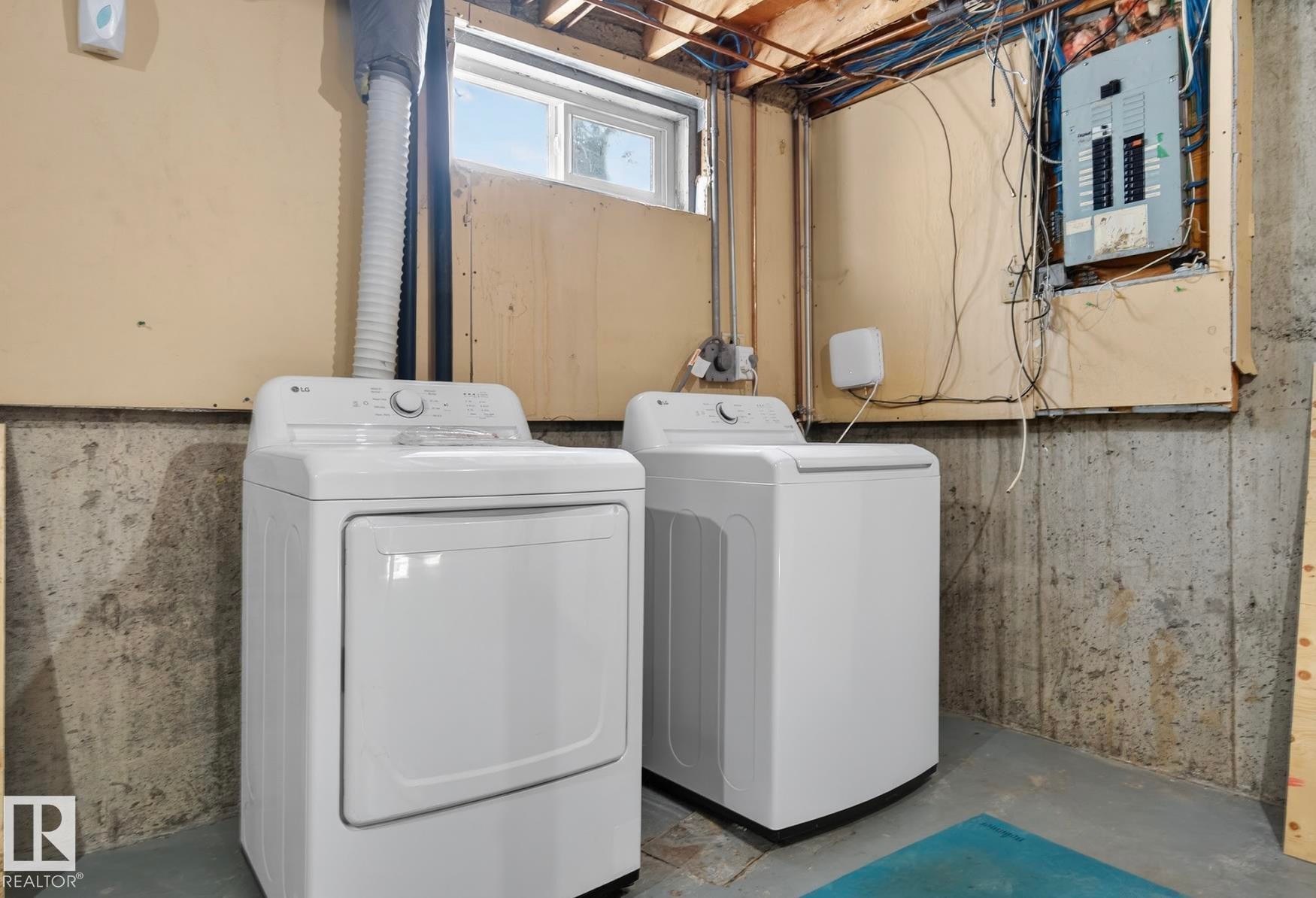 Laundry area with electric panel, washer and clothes dryer, and unfinished concrete floors - 9969 171 Ave, Edmonton, AB - Indoor Photo Showing Laundry Room