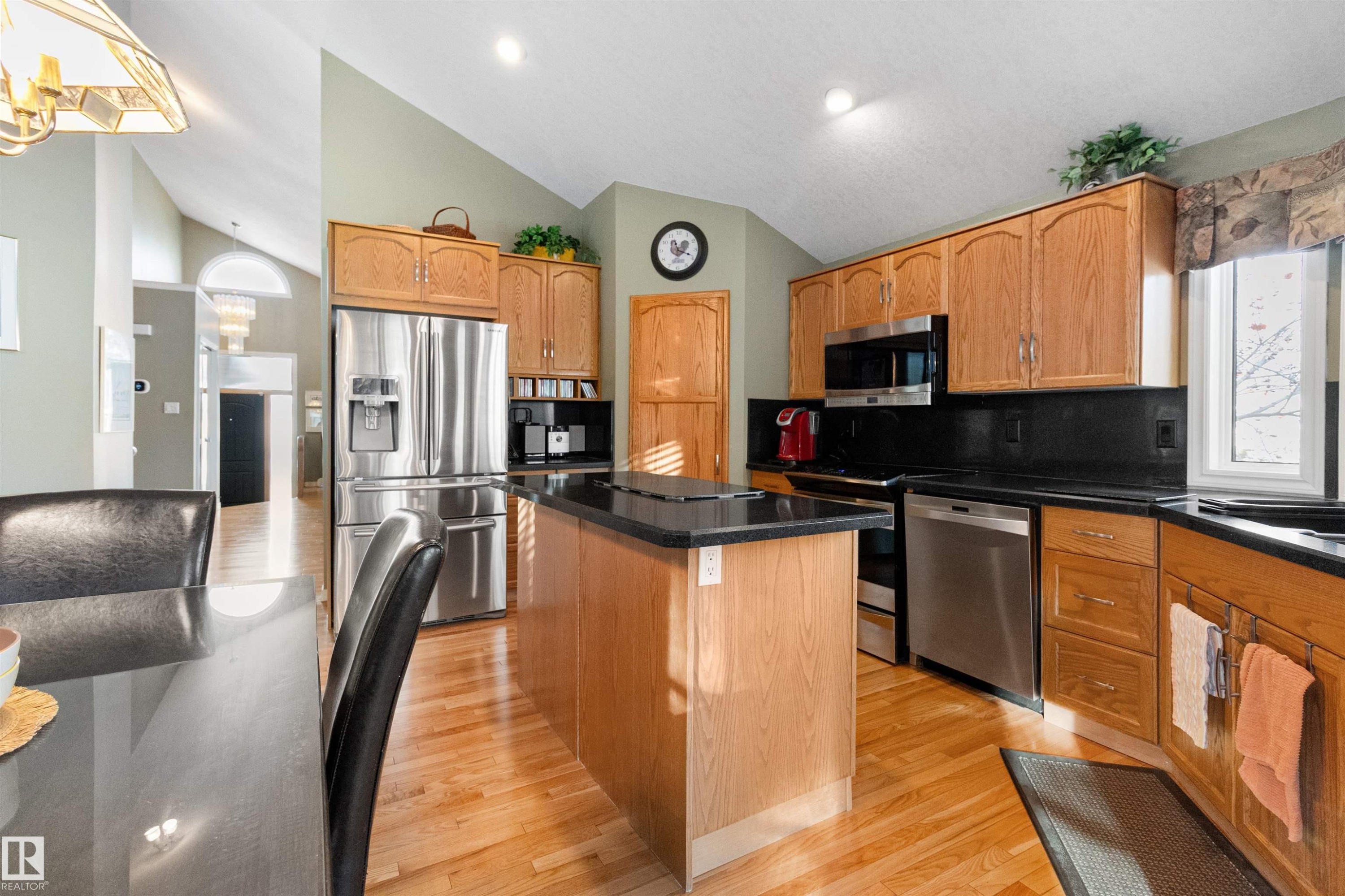 Kitchen featuring stainless steel appliances, a kitchen island, light wood-style flooring, lofted ceiling, and decorative backsplash - 519 Buchanan Road, Edmonton, AB - Indoor Photo Showing Kitchen