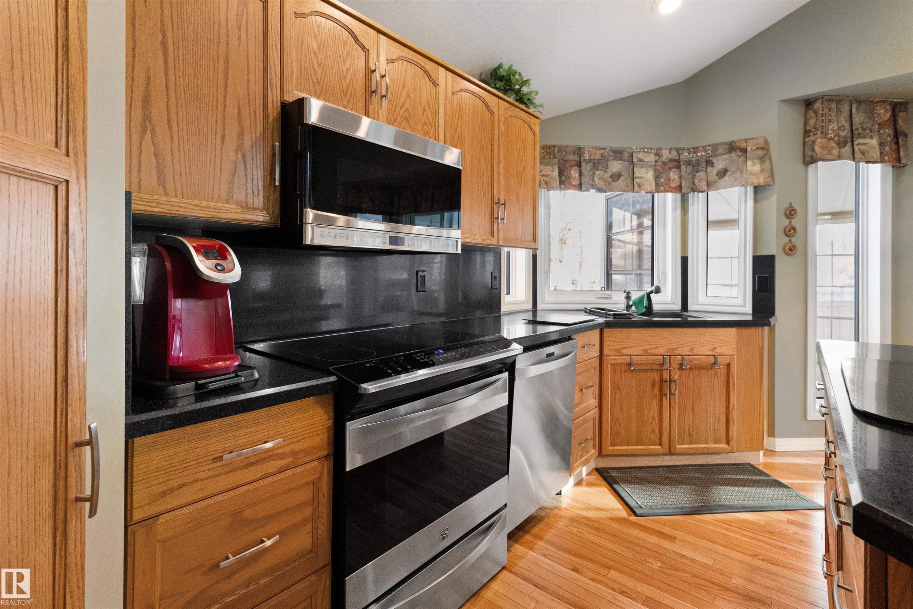 Kitchen featuring stainless steel appliances, light wood finished floors, wood finish cabinets, lofted ceiling, and decorative backsplash - 519 Buchanan Road, Edmonton, AB - Indoor Photo Showing Kitchen