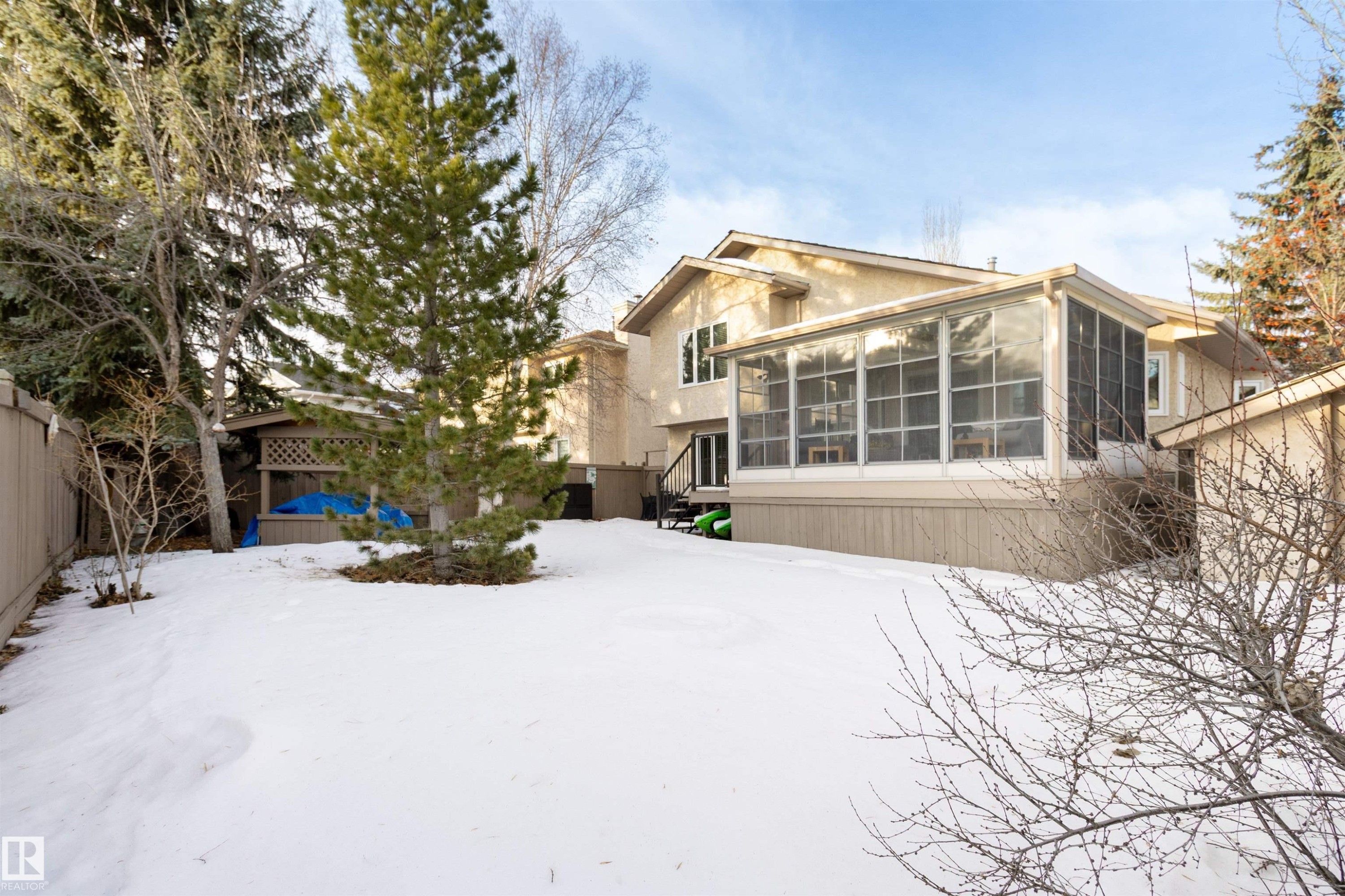 Snow covered back of property featuring a sunroom, a fenced backyard, and stucco siding - 519 Buchanan Road, Edmonton, AB - Outdoor