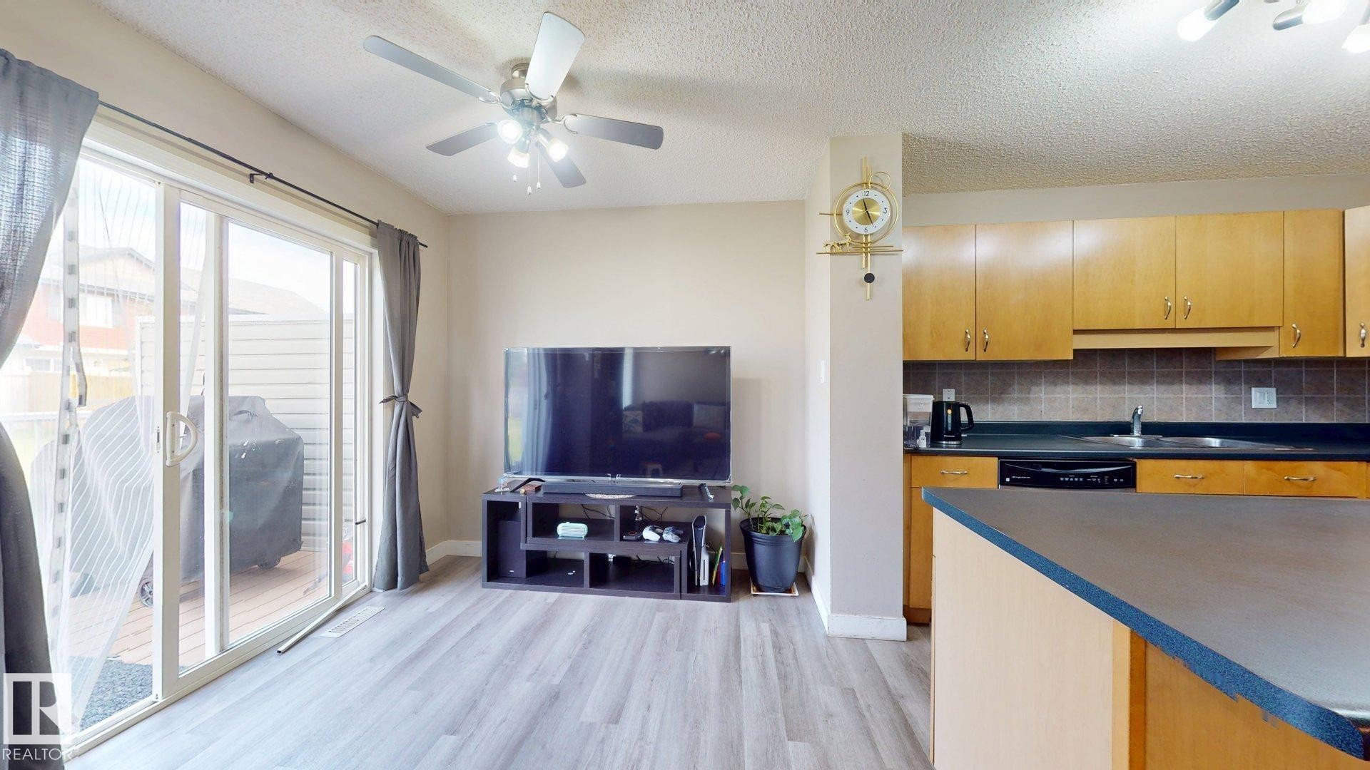 Kitchen with dark countertops, light wood-style floors, a textured ceiling, a ceiling fan, and decorative backsplash - 1150 37B Avenue, Edmonton, AB - Indoor