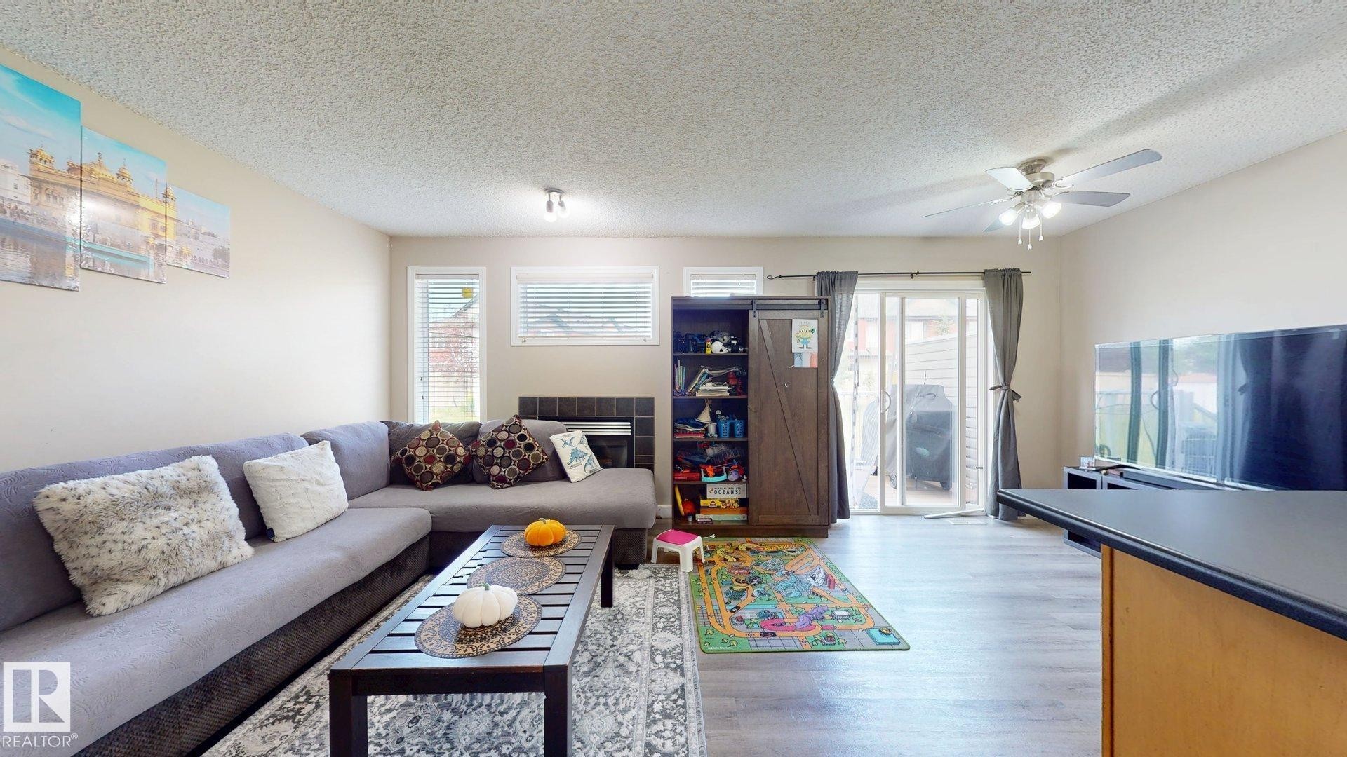 Living area featuring a textured ceiling, plenty of natural light, light wood-style floors, and a ceiling fan - 1150 37B Avenue, Edmonton, AB - Indoor Photo Showing Living Room