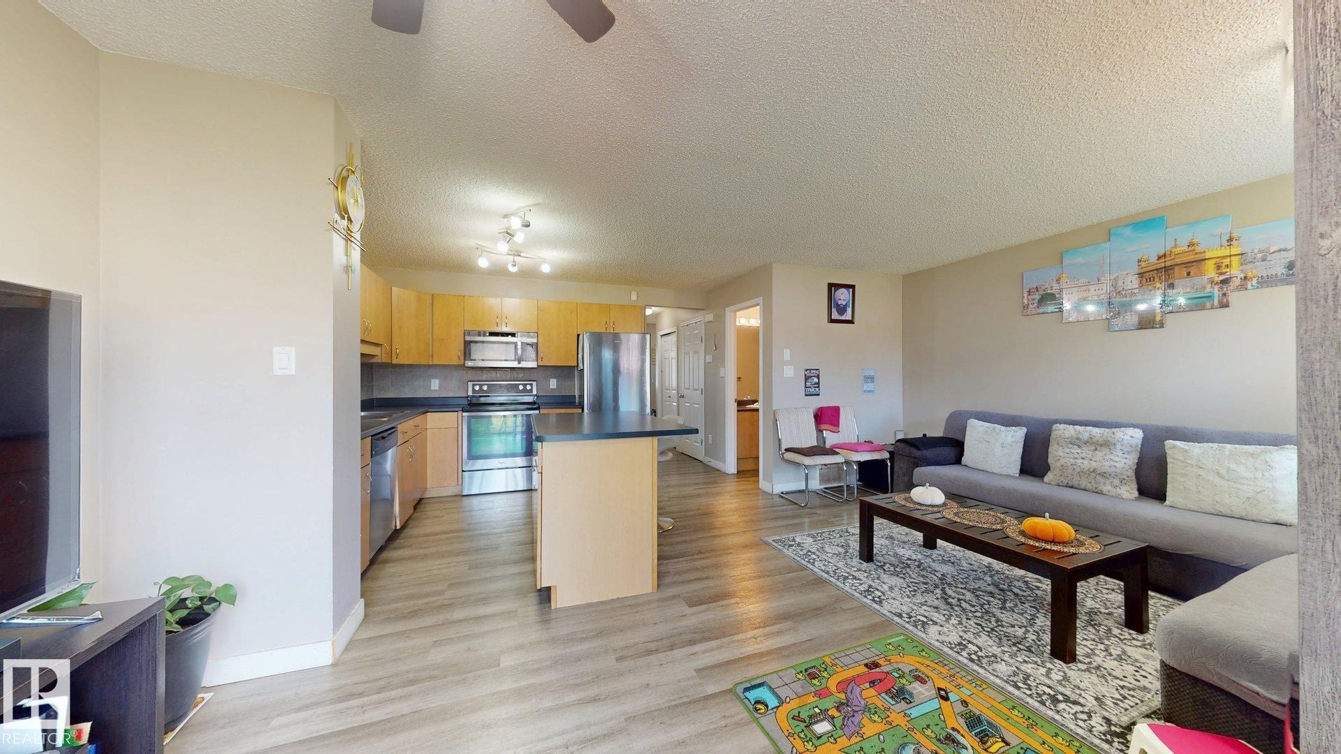 Living area with a textured ceiling, light wood-style floors, and a ceiling fan - 1150 37B Avenue, Edmonton, AB - Indoor