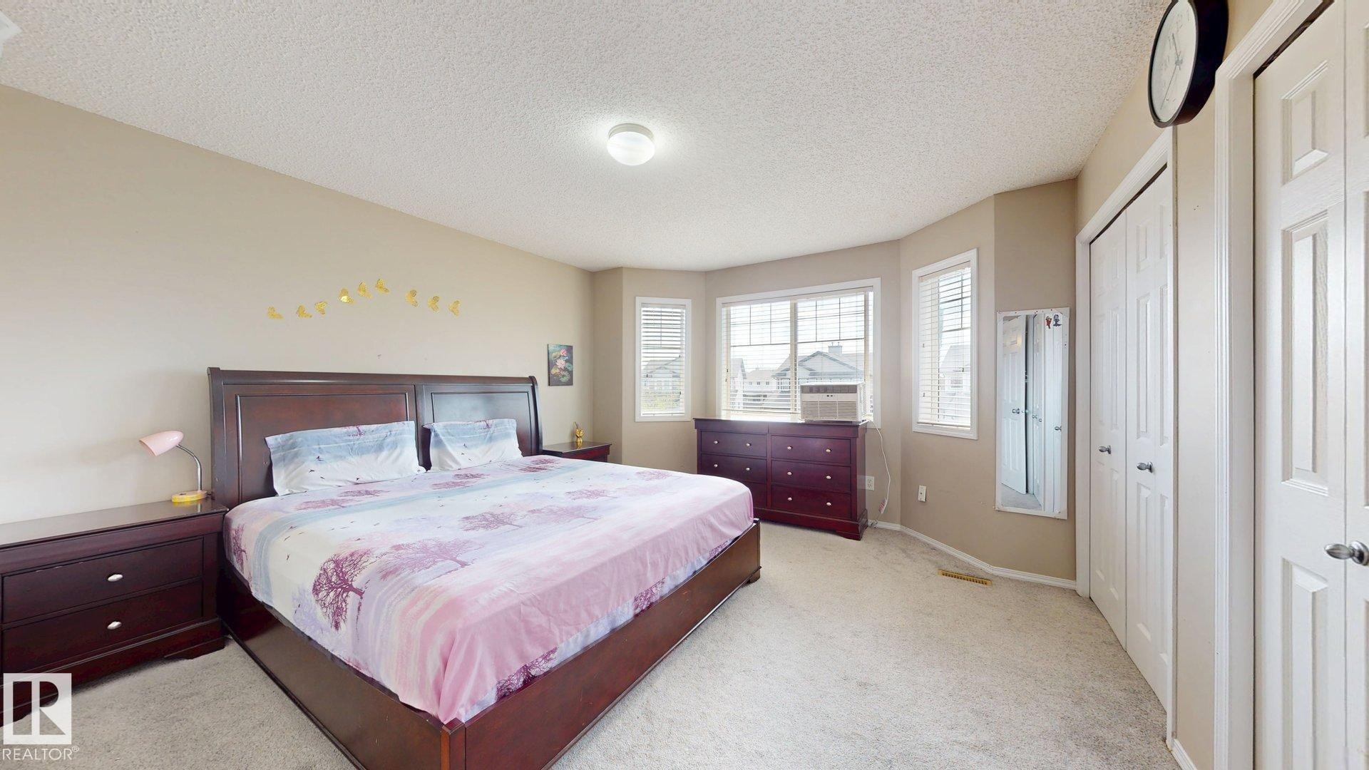 Bedroom with multiple closets, light carpet, and a textured ceiling - 1150 37B Avenue, Edmonton, AB - Indoor Photo Showing Bedroom