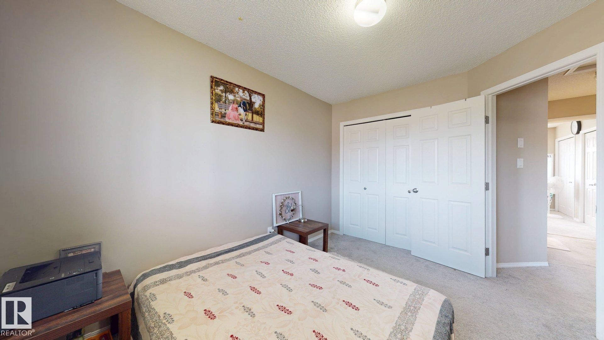 Bedroom with a textured ceiling, light carpet, and a closet - 1150 37B Avenue, Edmonton, AB - Indoor Photo Showing Bedroom