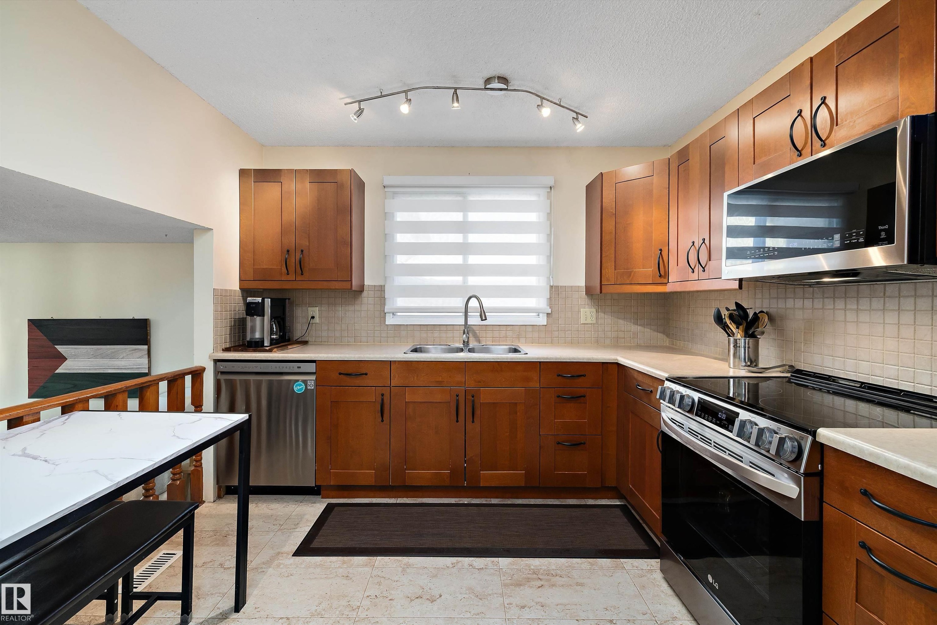 Kitchen featuring stainless steel appliances, wood finish cabinetry, and backsplash - 9804 156 Avenue, Edmonton, AB - Indoor Photo Showing Kitchen With Stainless Steel Kitchen With Double Sink